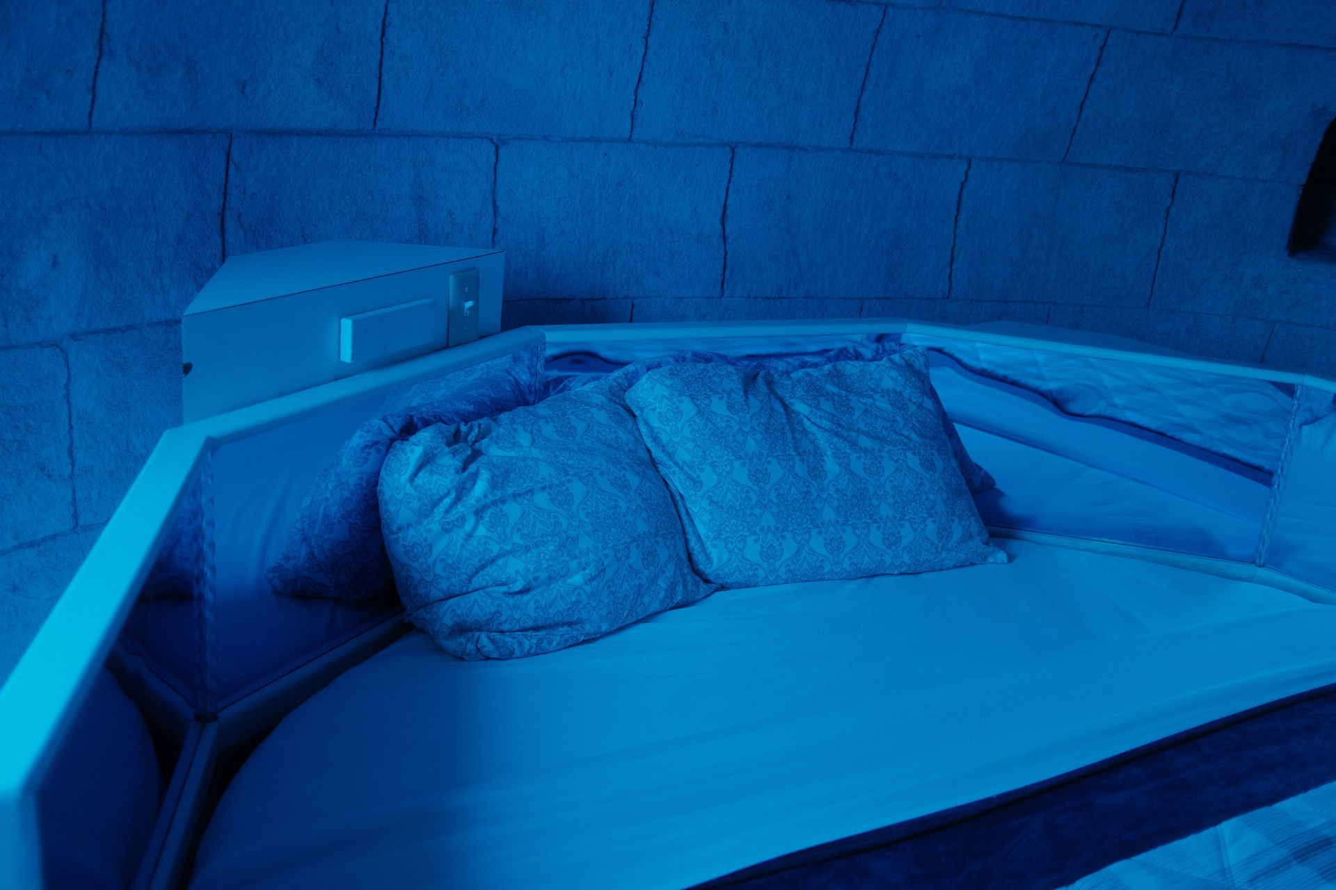 A bed with two pillows on it in a room with blue lights.