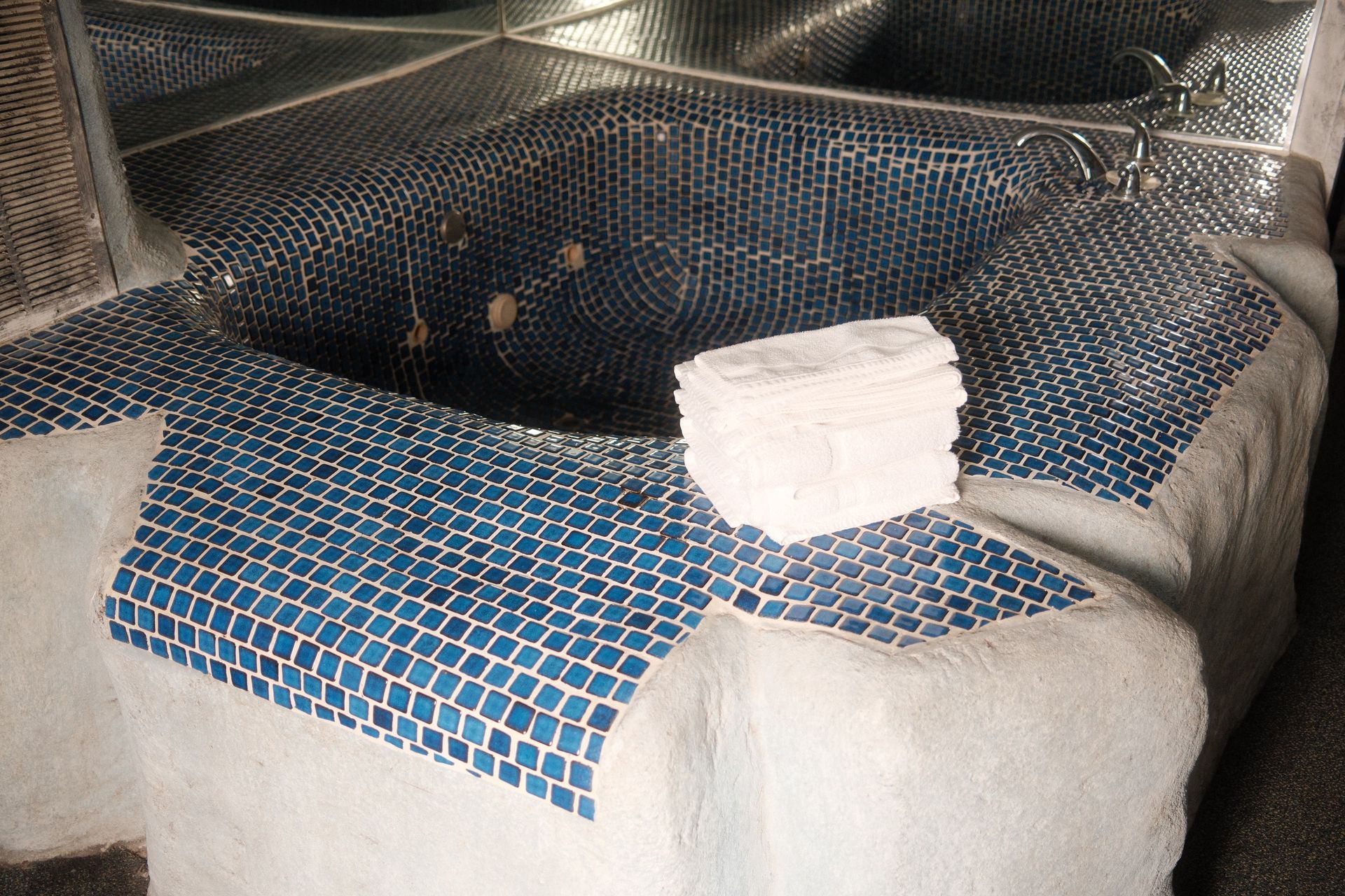 A bathtub with blue tiles and a towel on the edge