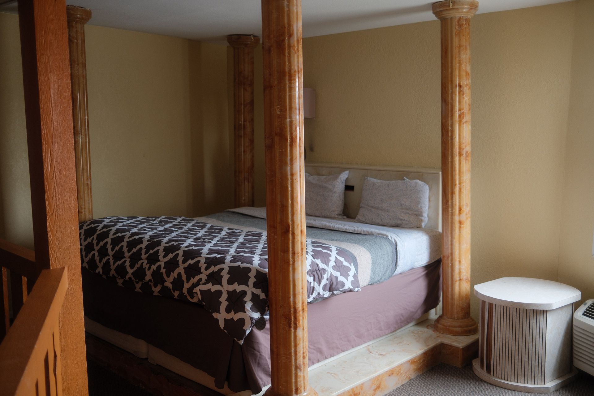 A hotel room with a canopy bed and wooden columns.