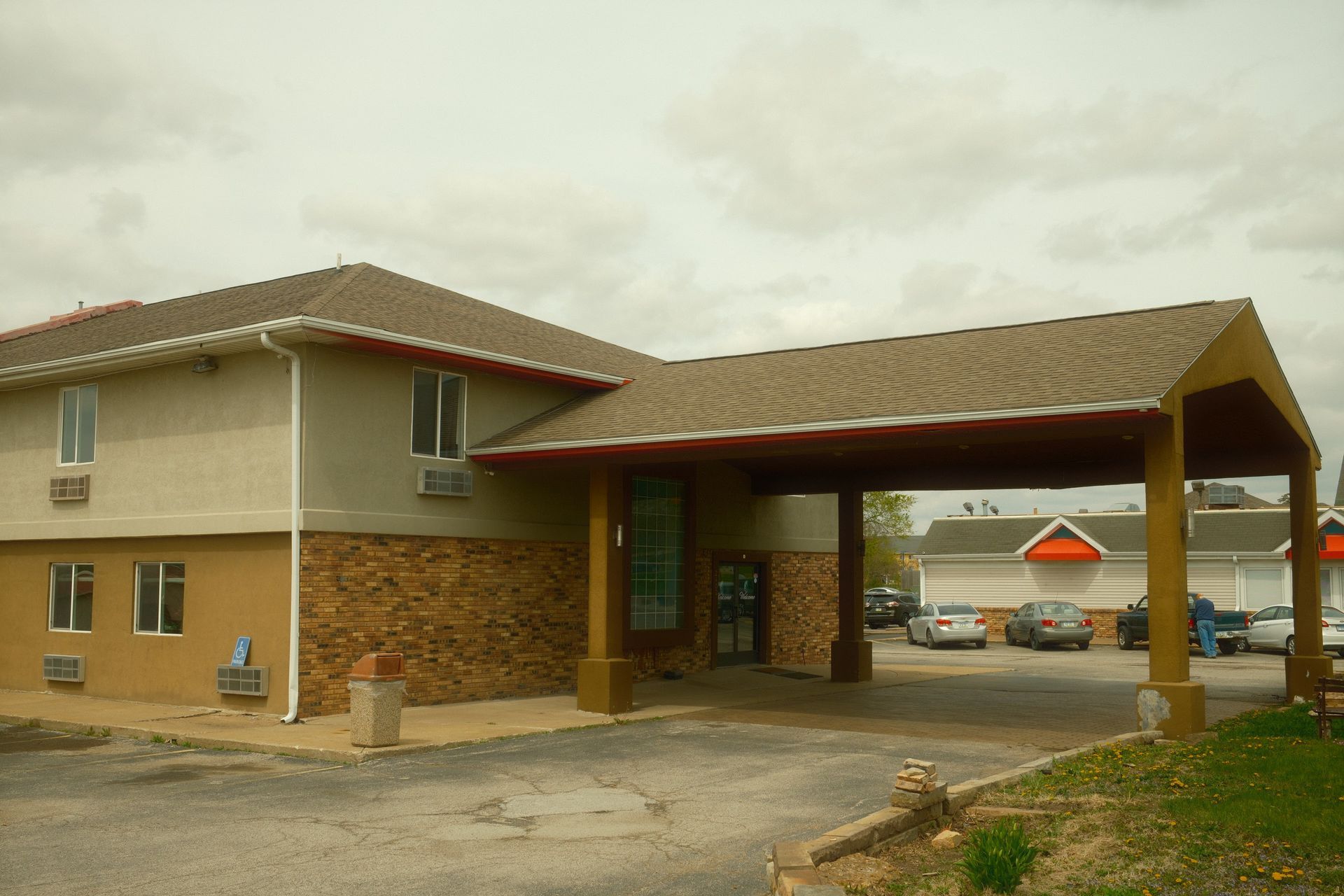 A hotel with cars parked in front of it on a cloudy day