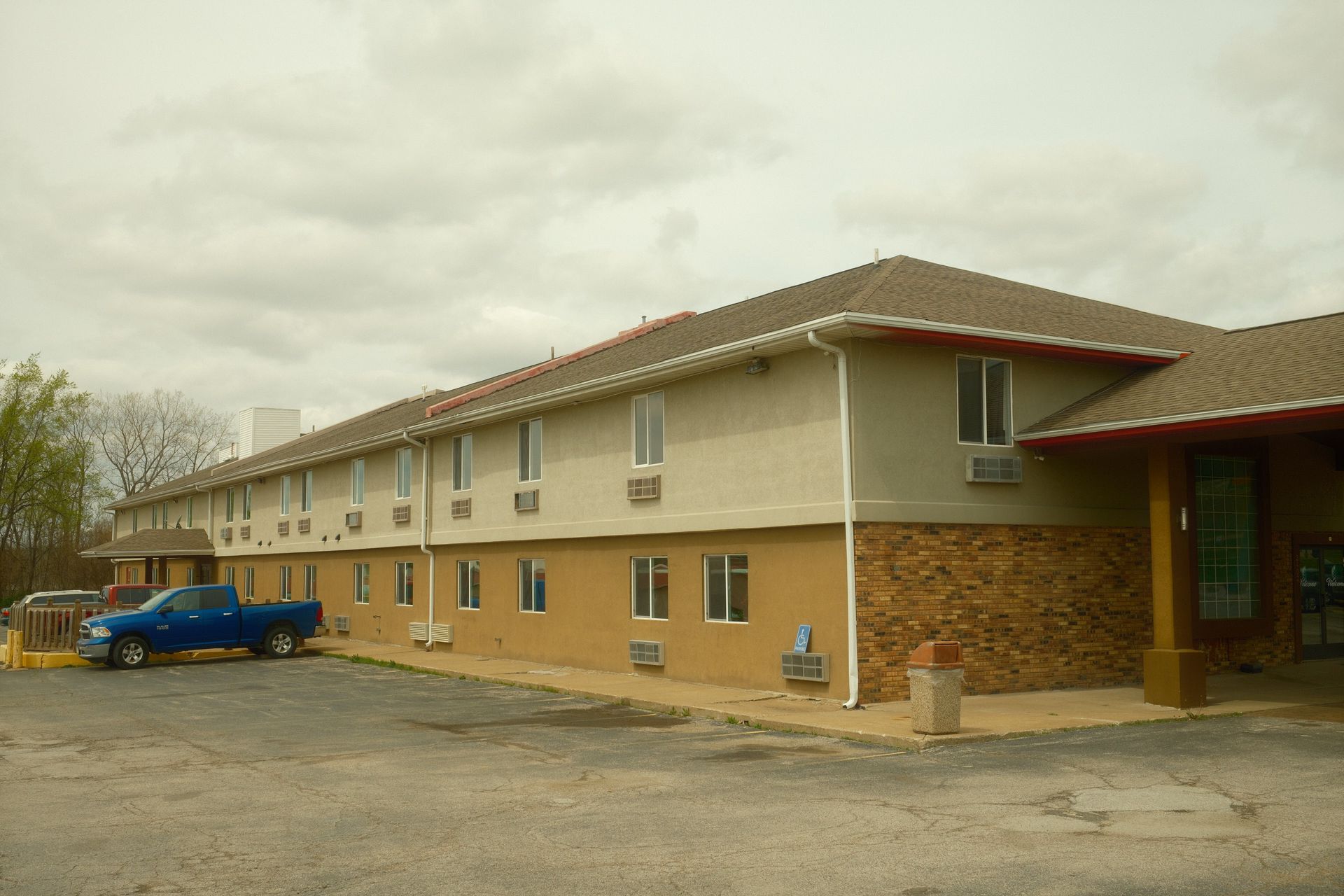 A blue truck is parked in front of a large building