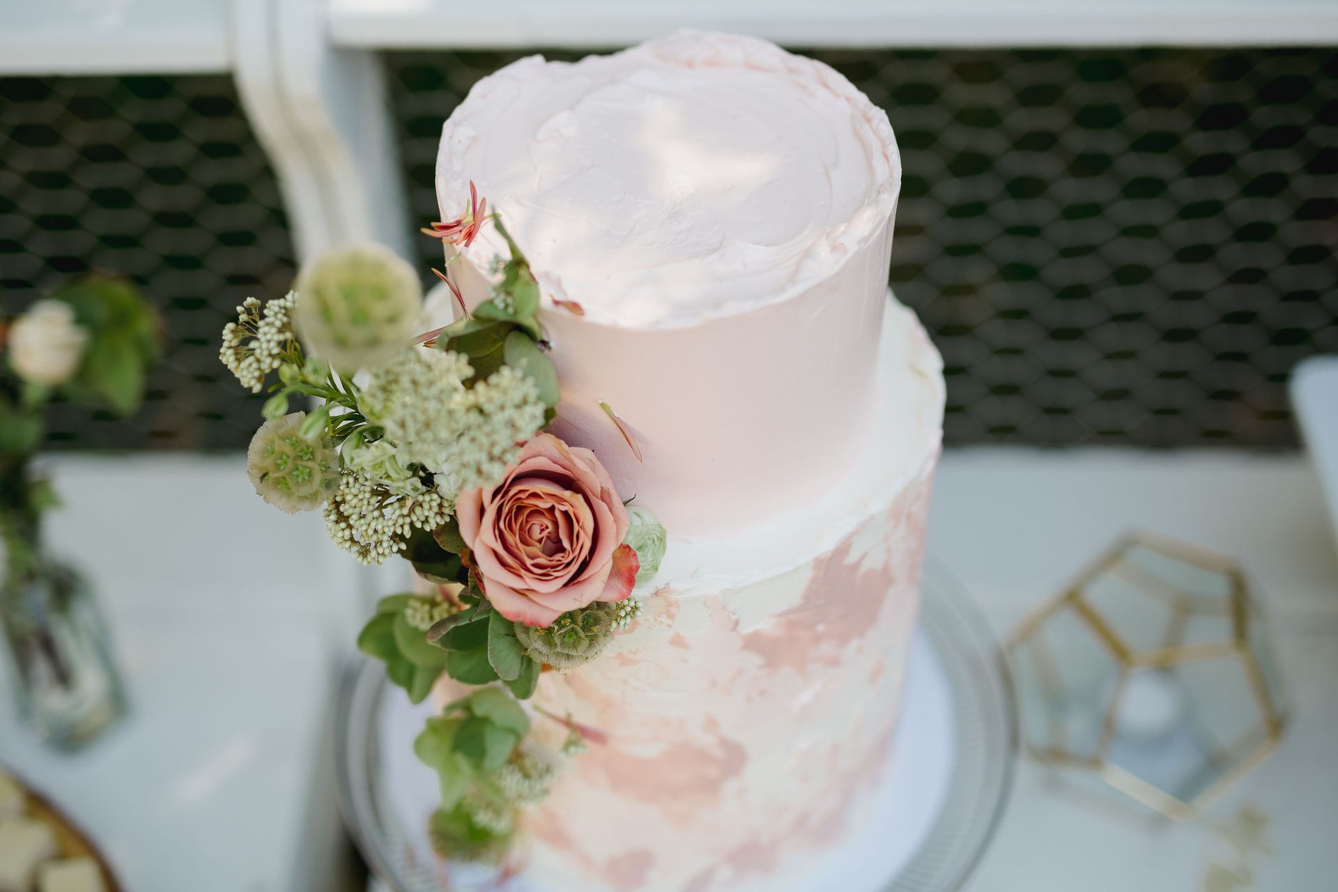 Two-tiered cake in blush and neutral tones, decorated with fresh flowers