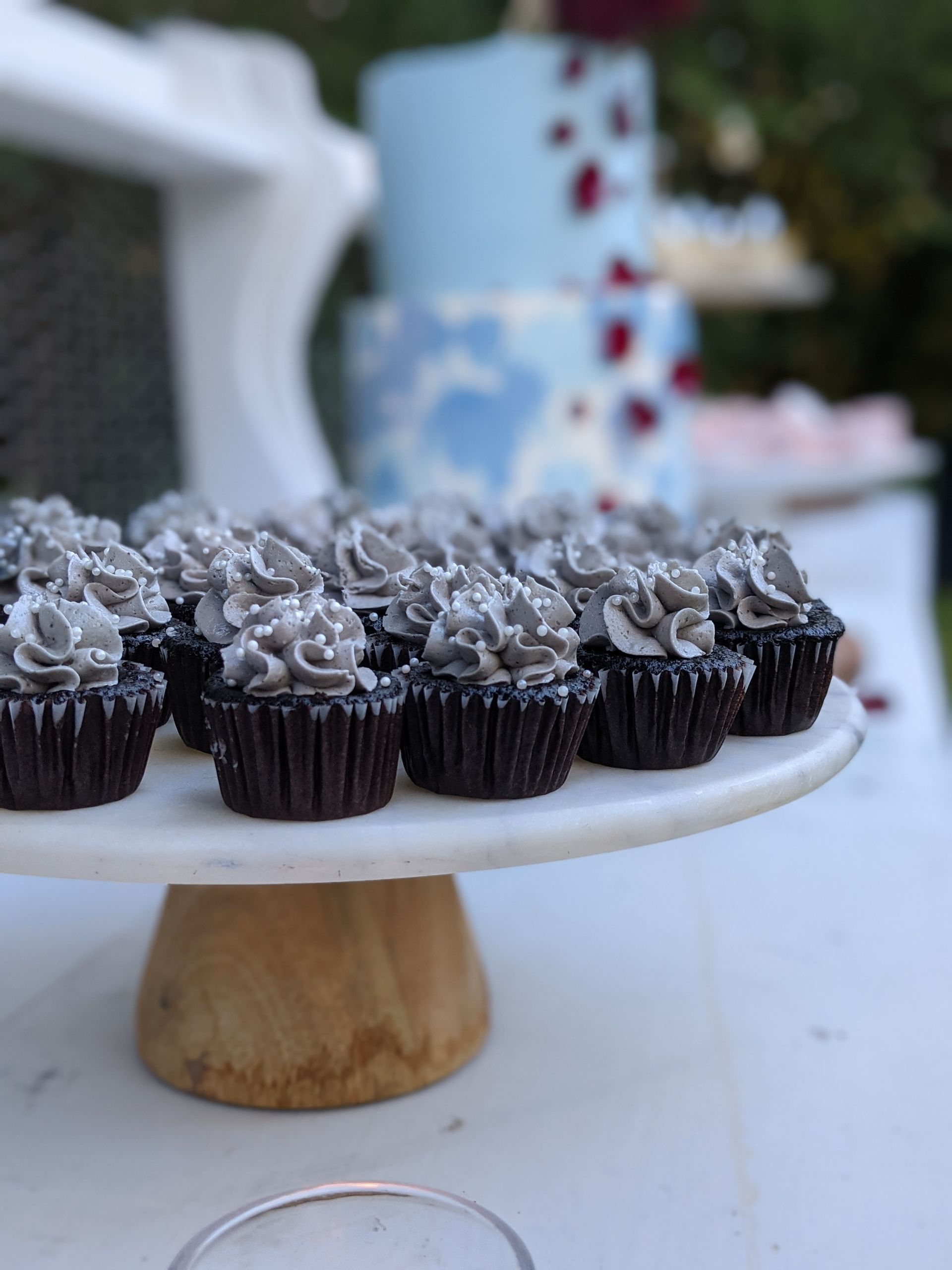 chocolate cupcakes with cookies and cream buttercream on a dessert table with two tiered cake for wedding