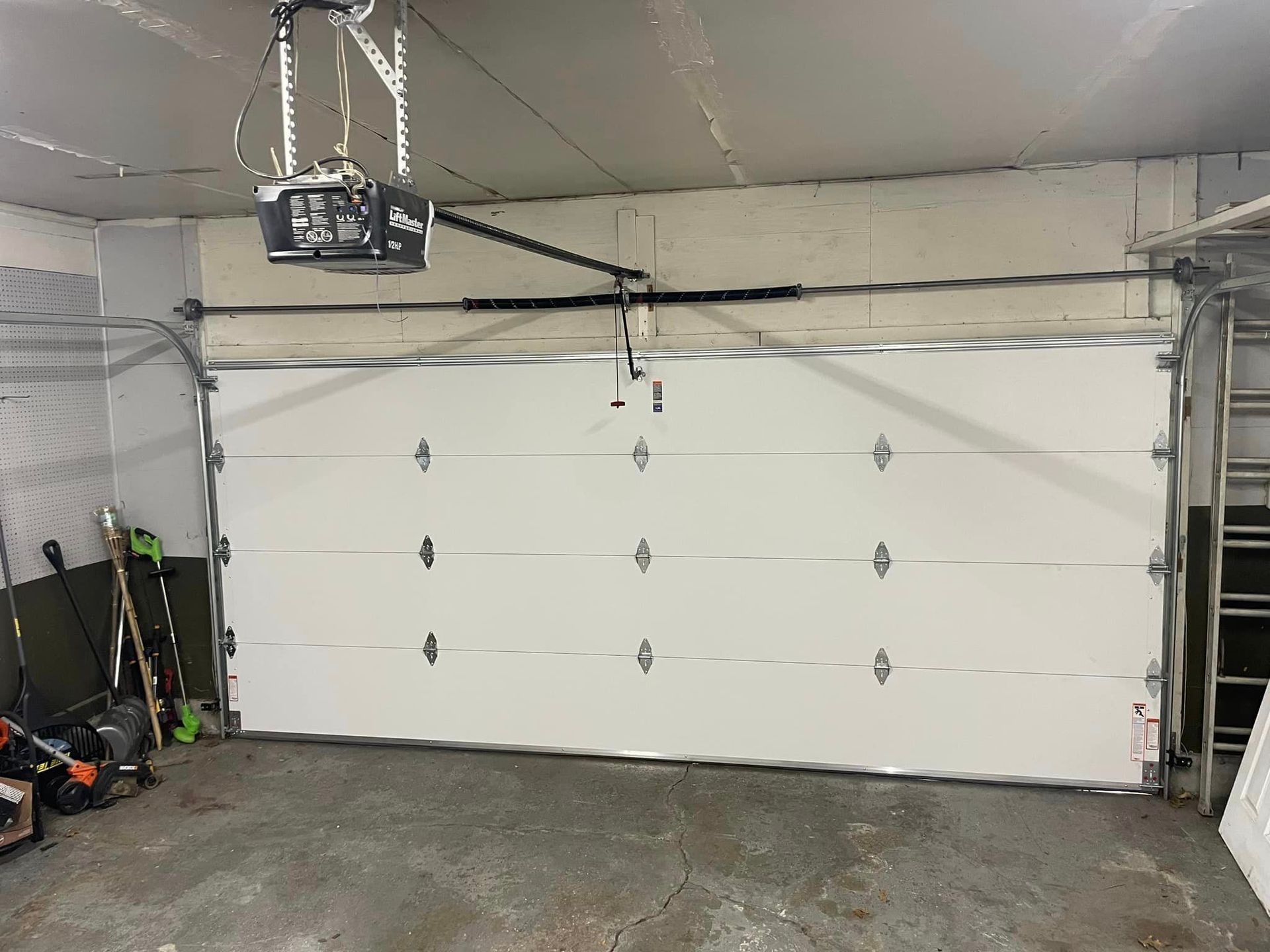 House exterior with a black garage door and beige siding, viewed from the driveway