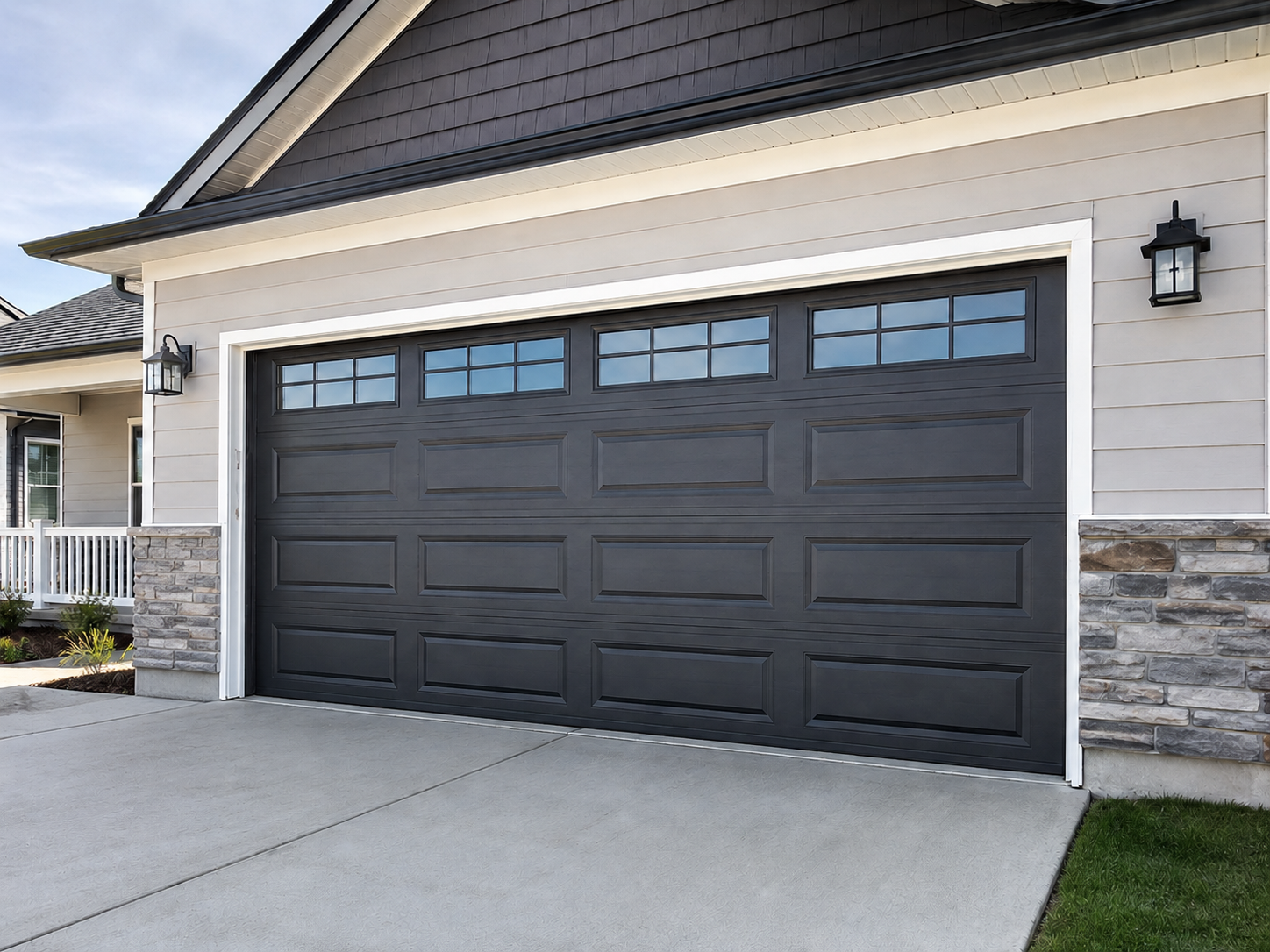 Dark gray double garage door on a suburban house with stone siding and a concrete driveway