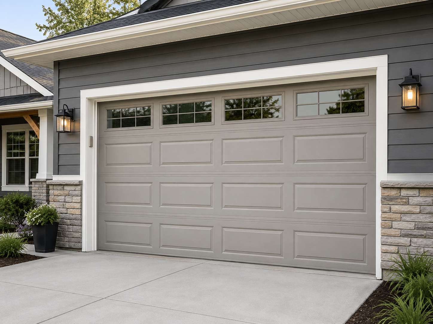 Modern gray house exterior with a double garage door, stone accents, and front porch lights