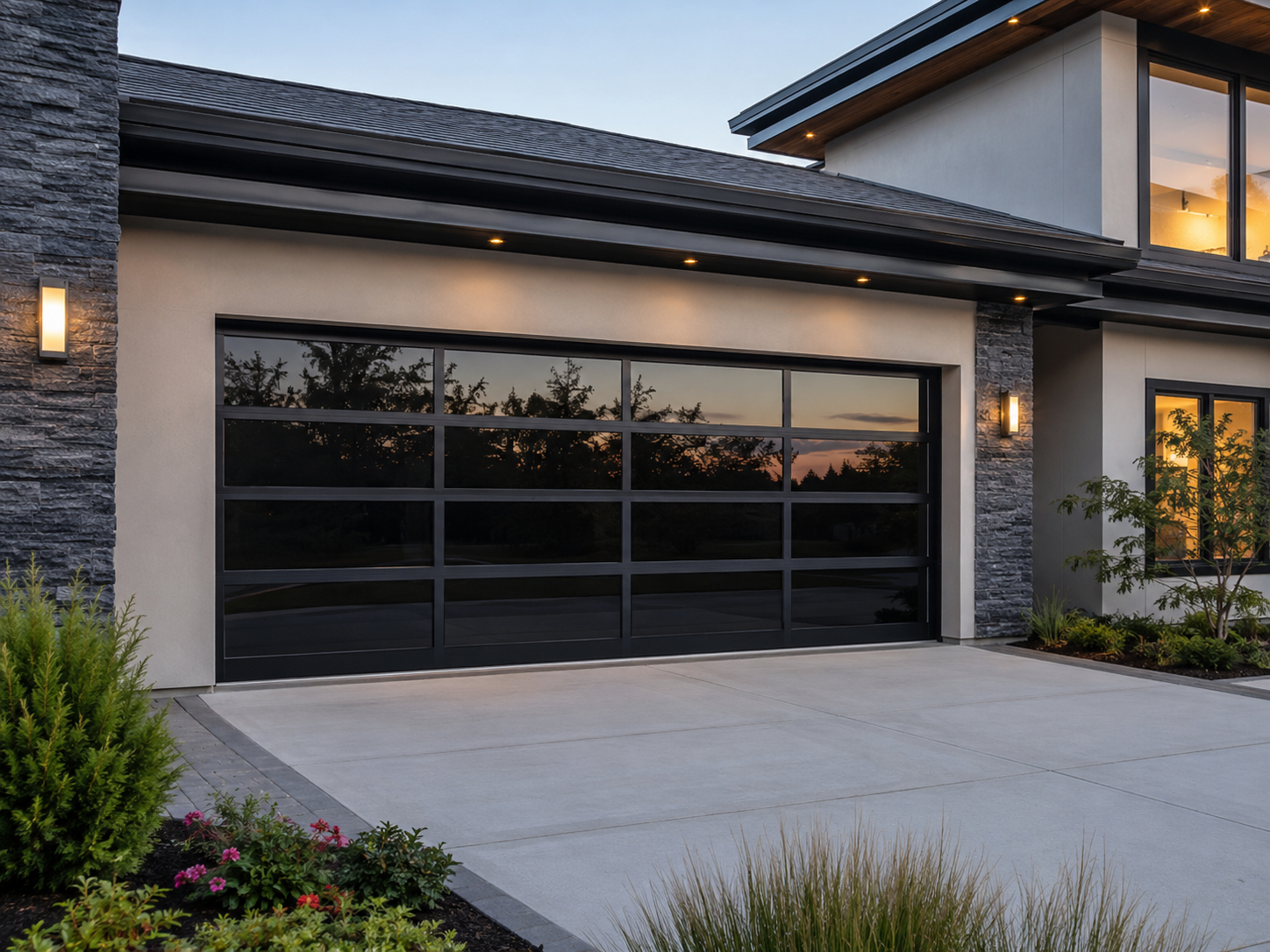 Modern house exterior with a black garage door, driveway, and evening sunset reflections on the windows