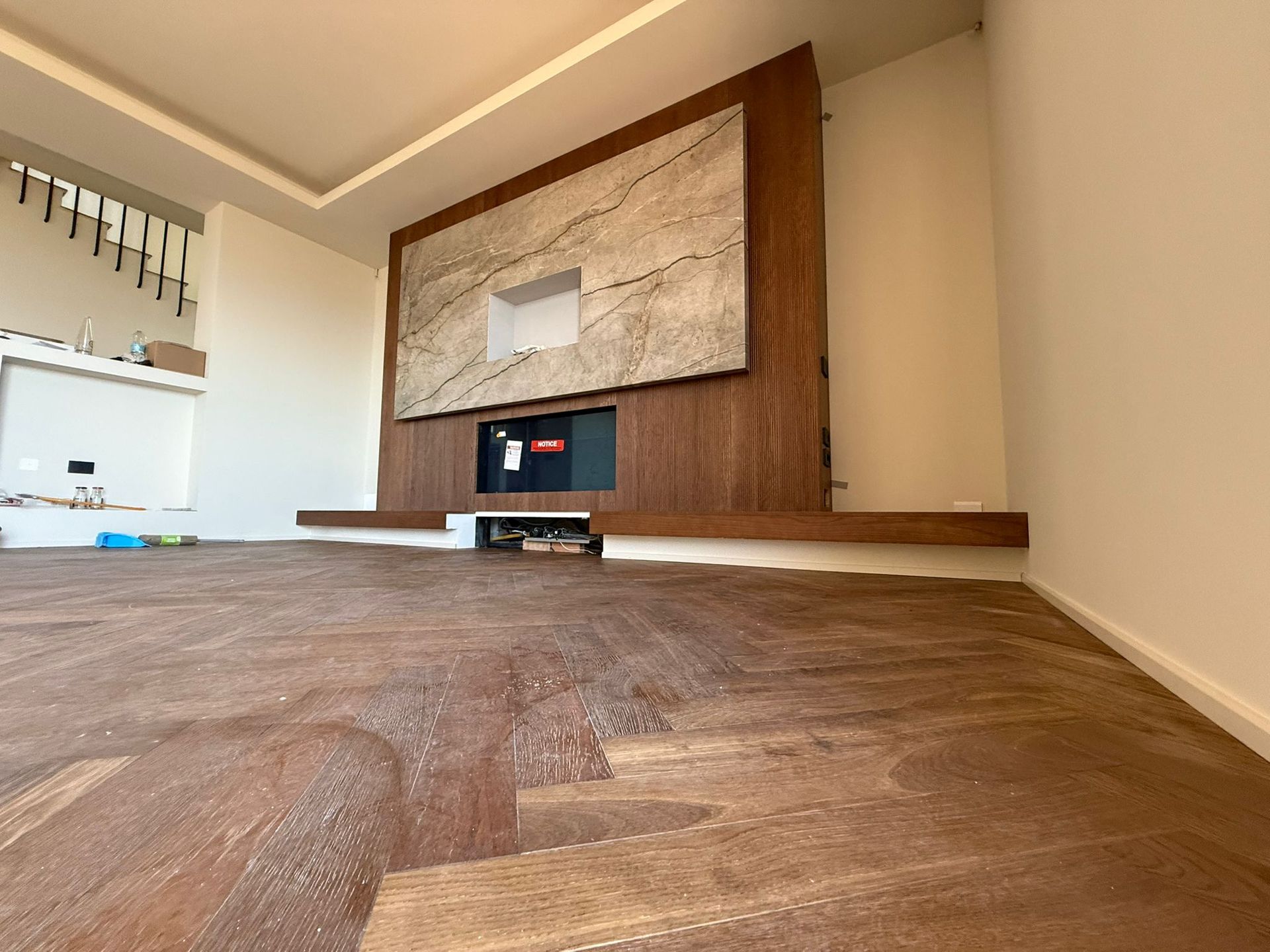 Un soggiorno moderno con pavimento in legno a spina di pesce, una parete centrale con rivestimento in pietra e un camino.