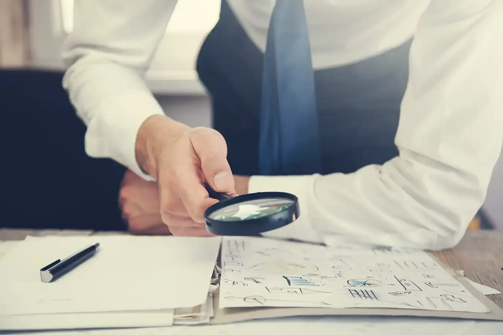 A man is looking through a magnifying glass at a piece of paper.
