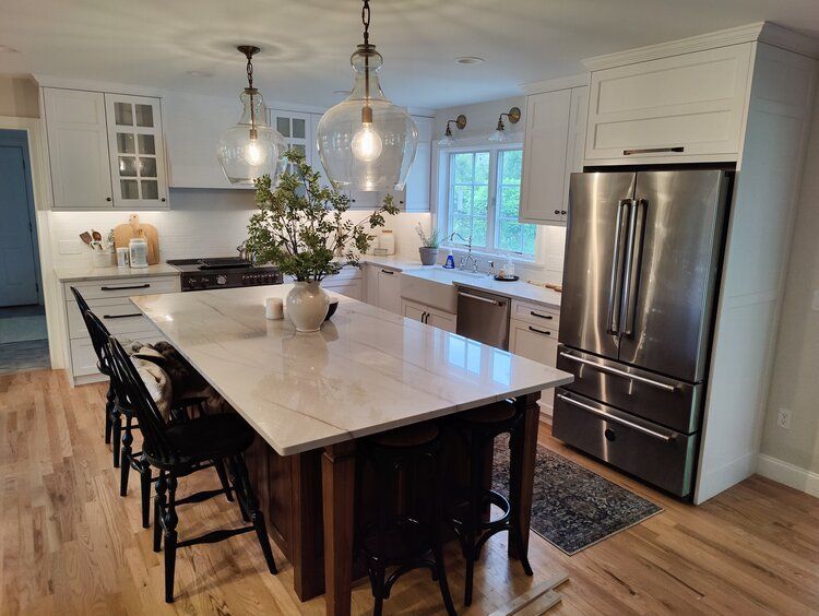 Custom kitchen and island. White cabinets, stone countertops that are white. Wood floor.