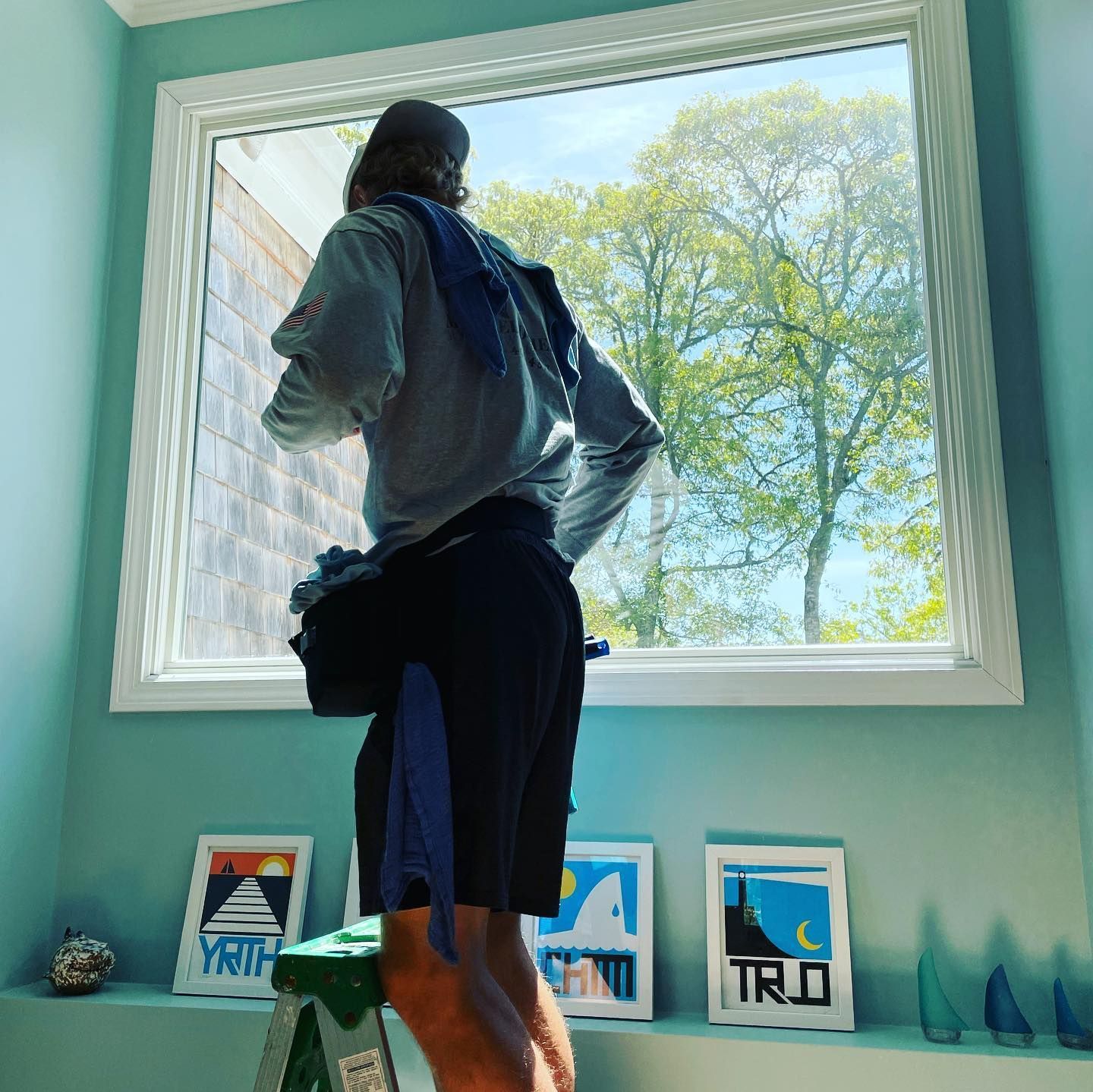 Technician performing window cleaning on large interior glass window in Cape Cod home