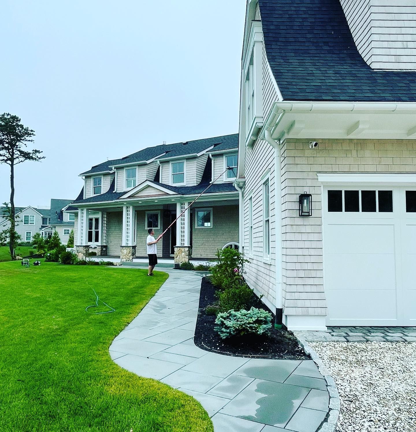 Professional window cleaning service on large Cape Cod property with manicured lawn