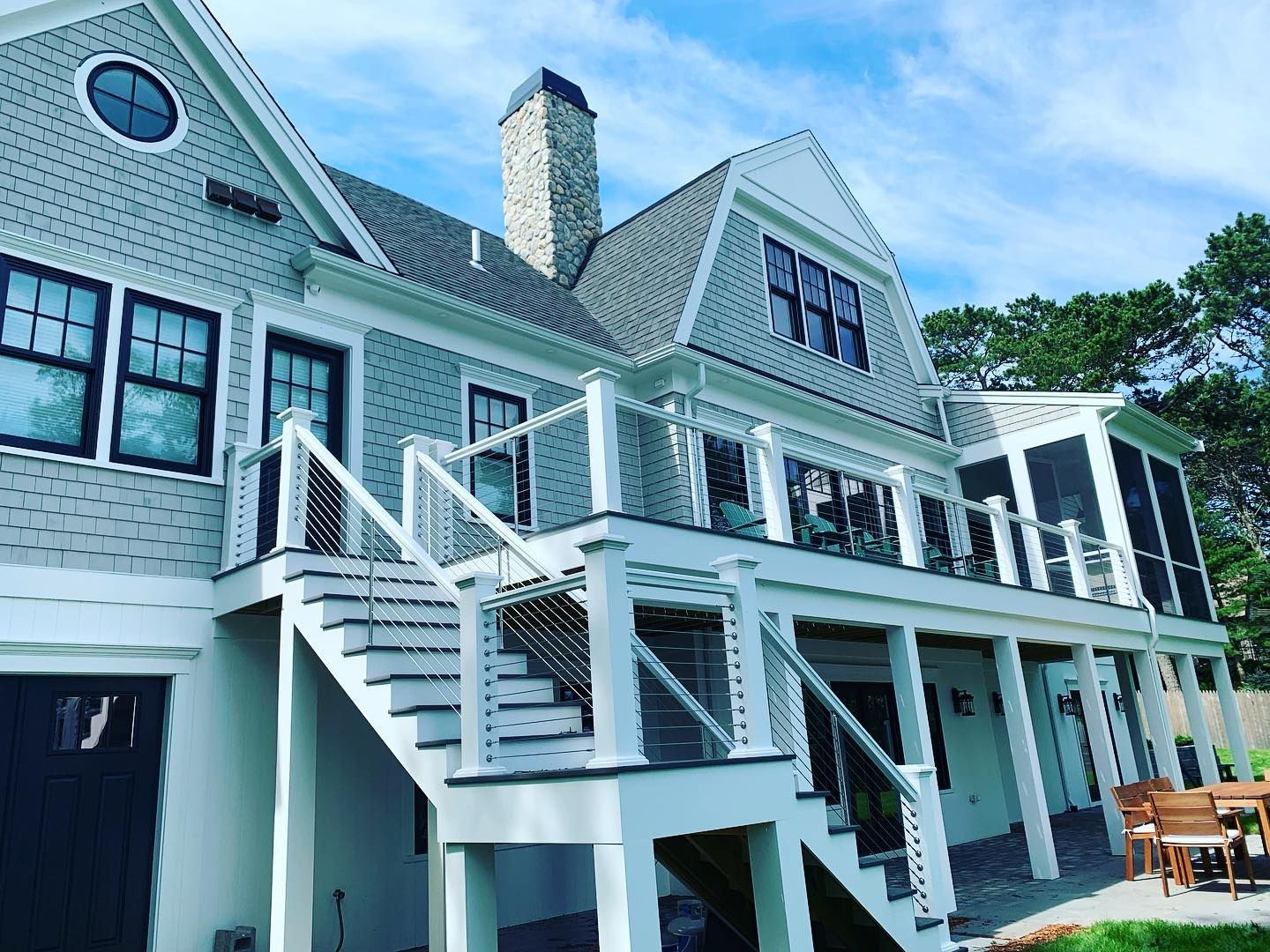 A large house with stairs leading up to the second floor and a screened in porch.