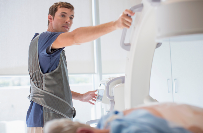 A man is preparing a patient for an x-ray in a hospital.