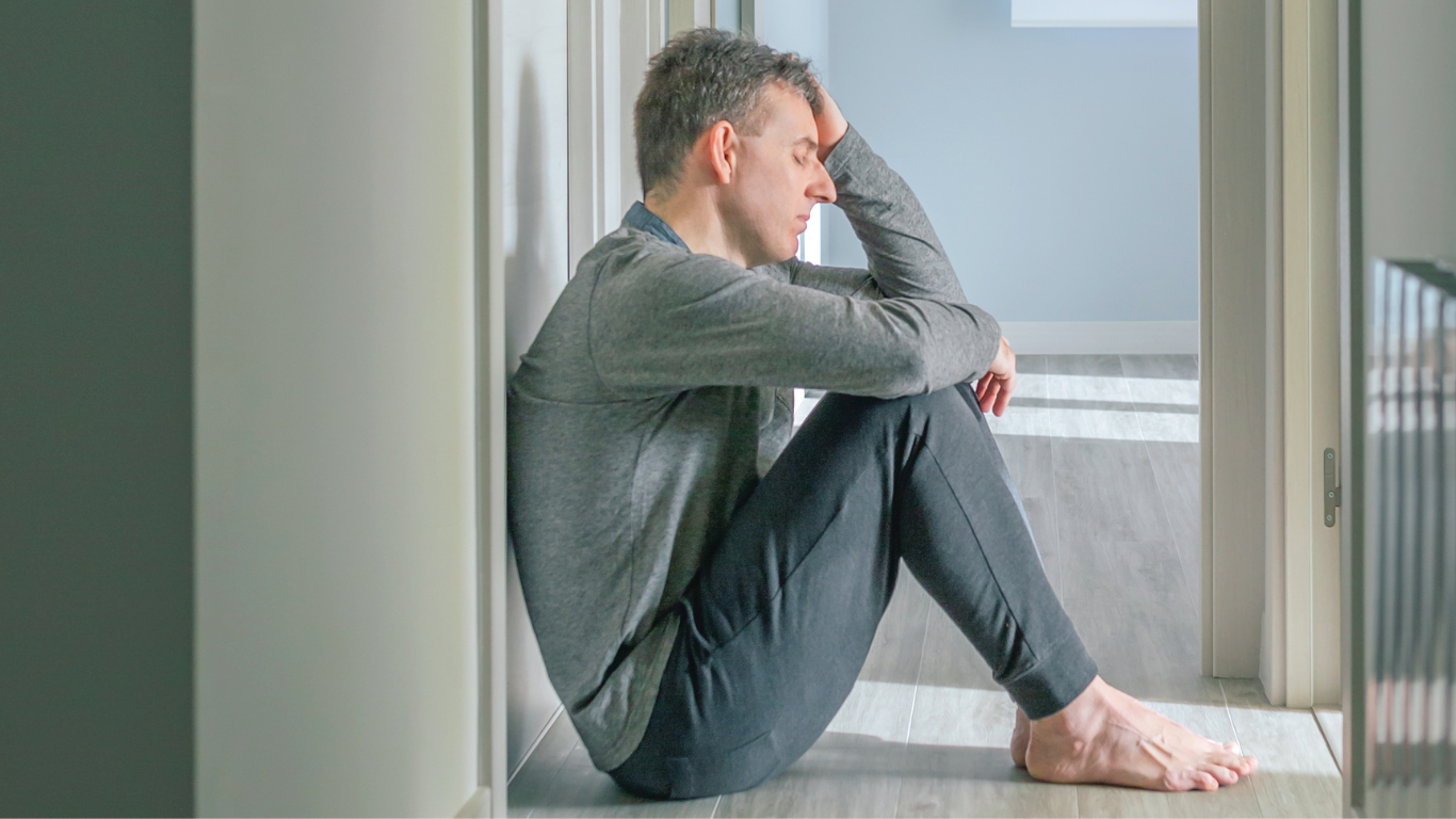 A woman is sitting on the ground with her head in her hands.
