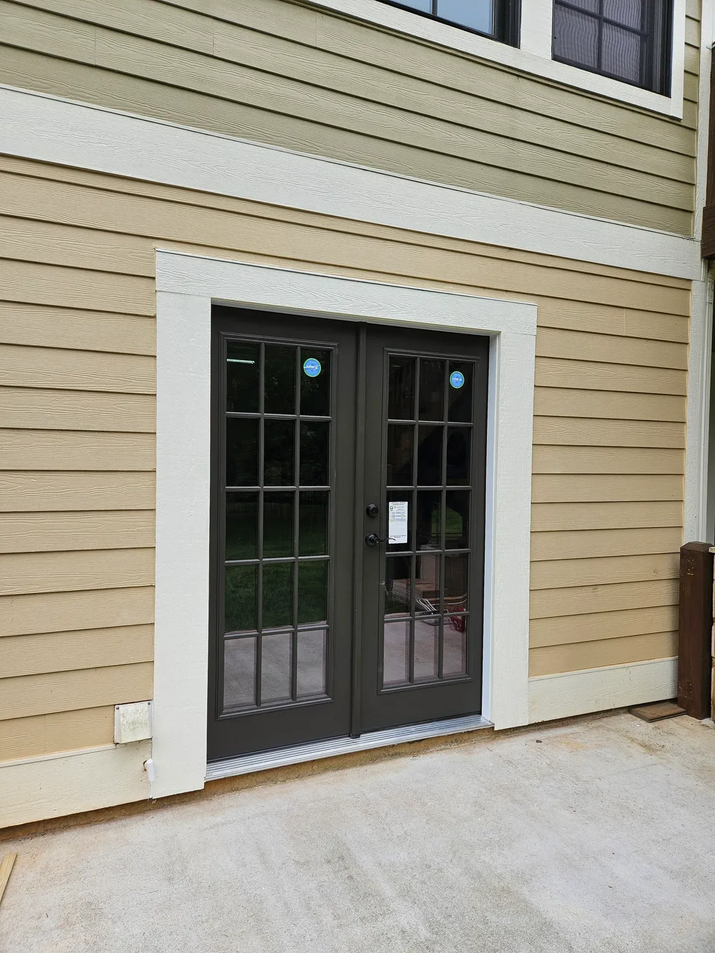 Exterior double doors with glass panes, framed in white trim, and a concrete patio.