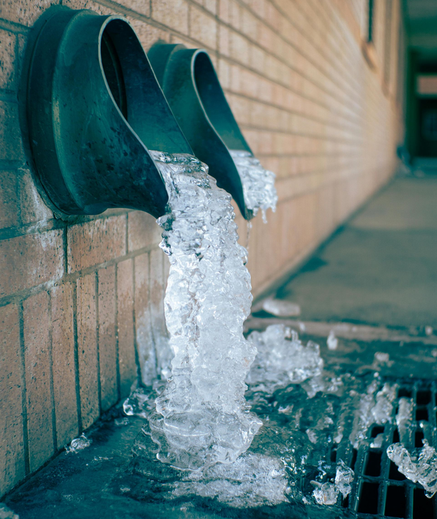 green pipes outside of commercial business with frozen pipes and ice coming out of them