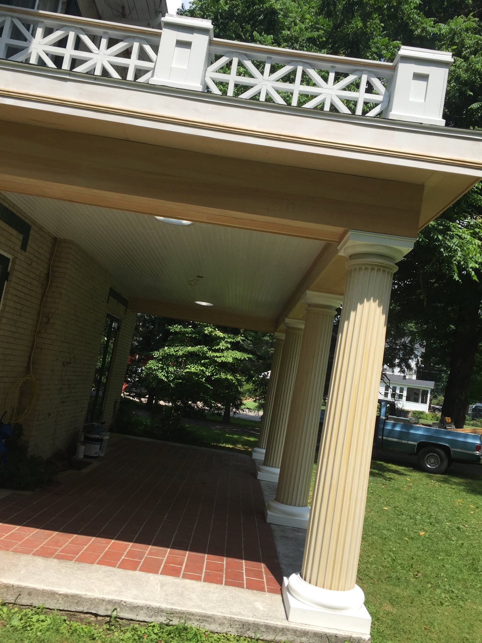 Beige porch with decorative columns and red brick floor.