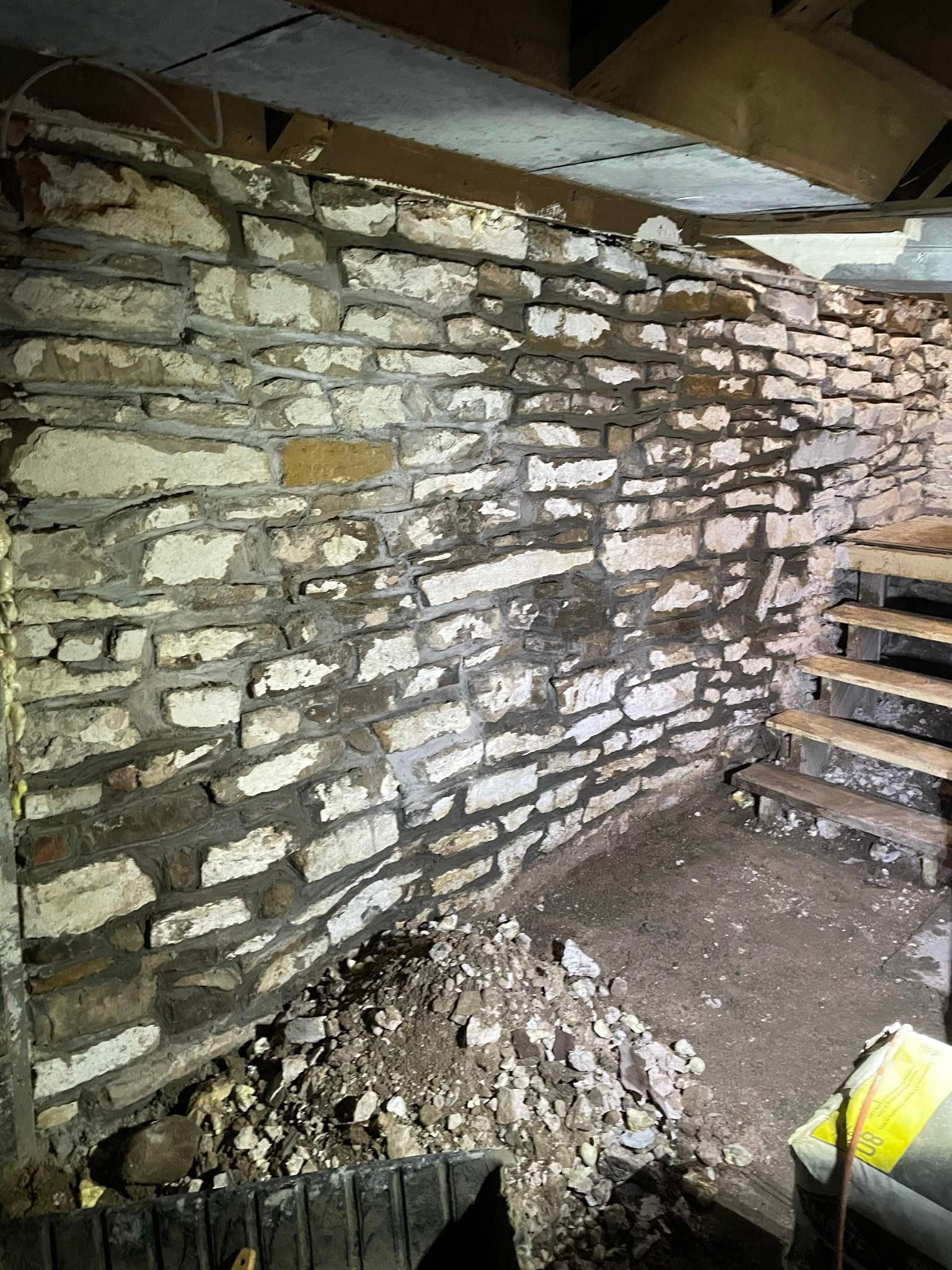 Stone foundation wall, partially obscured by debris and stairs.
