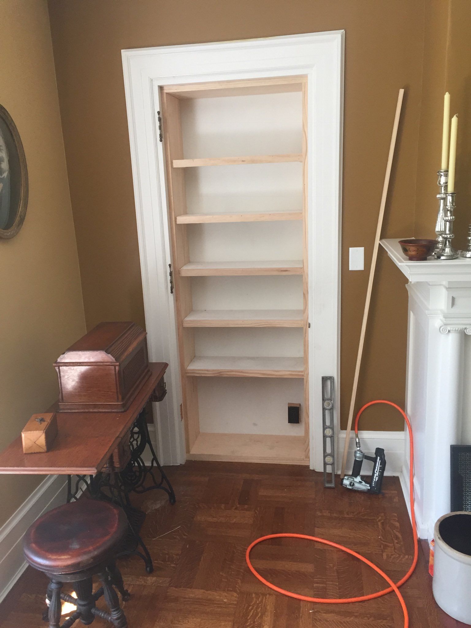 Built-in bookshelf in a room with tan walls, a sewing machine, and a fireplace.