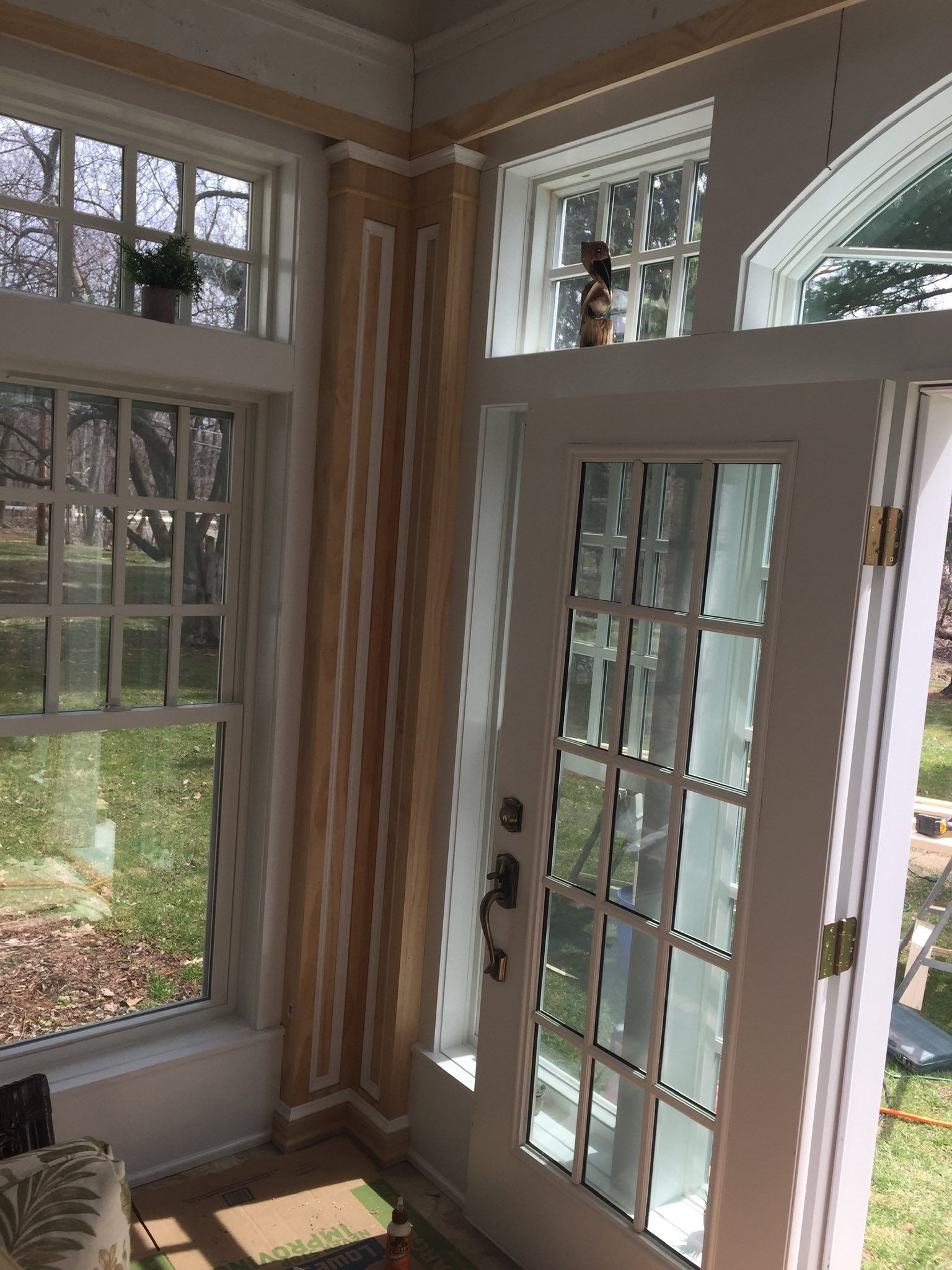 Sunroom corner with door and windows, striped wall, light brown and white, bright natural light.