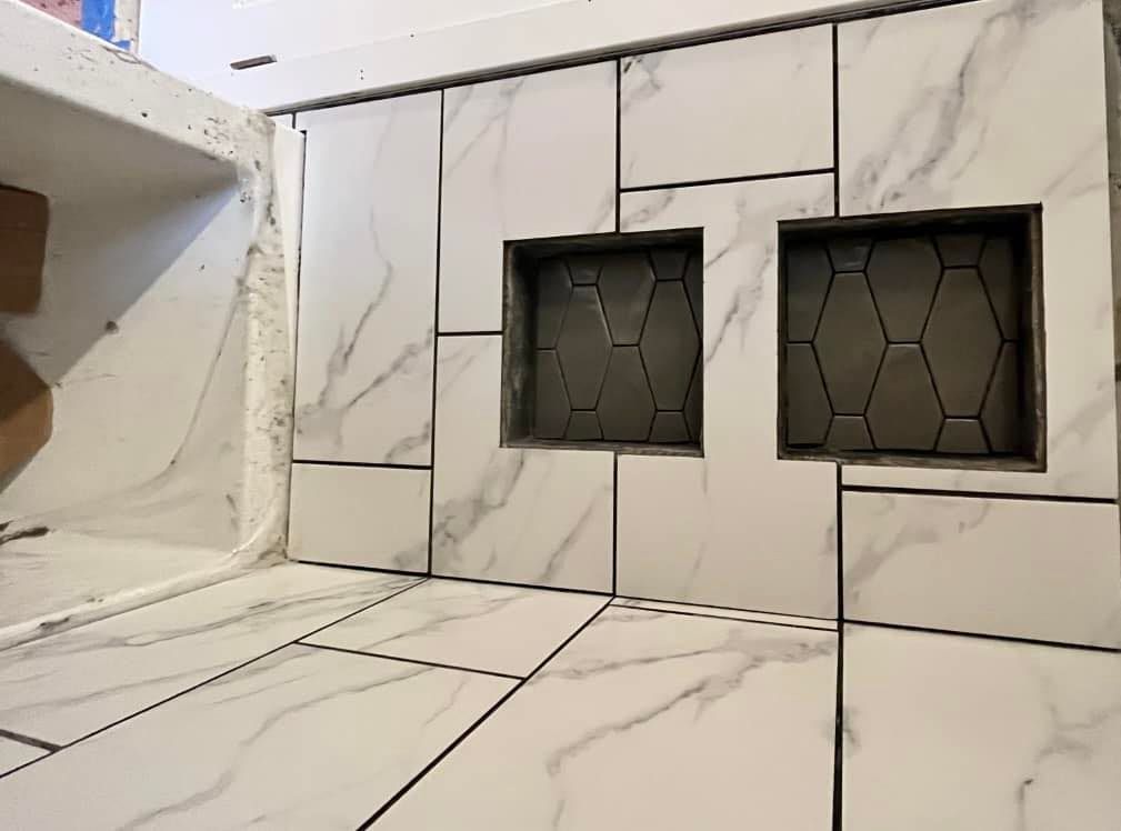 A bathroom with marble tiles and two shower niches.