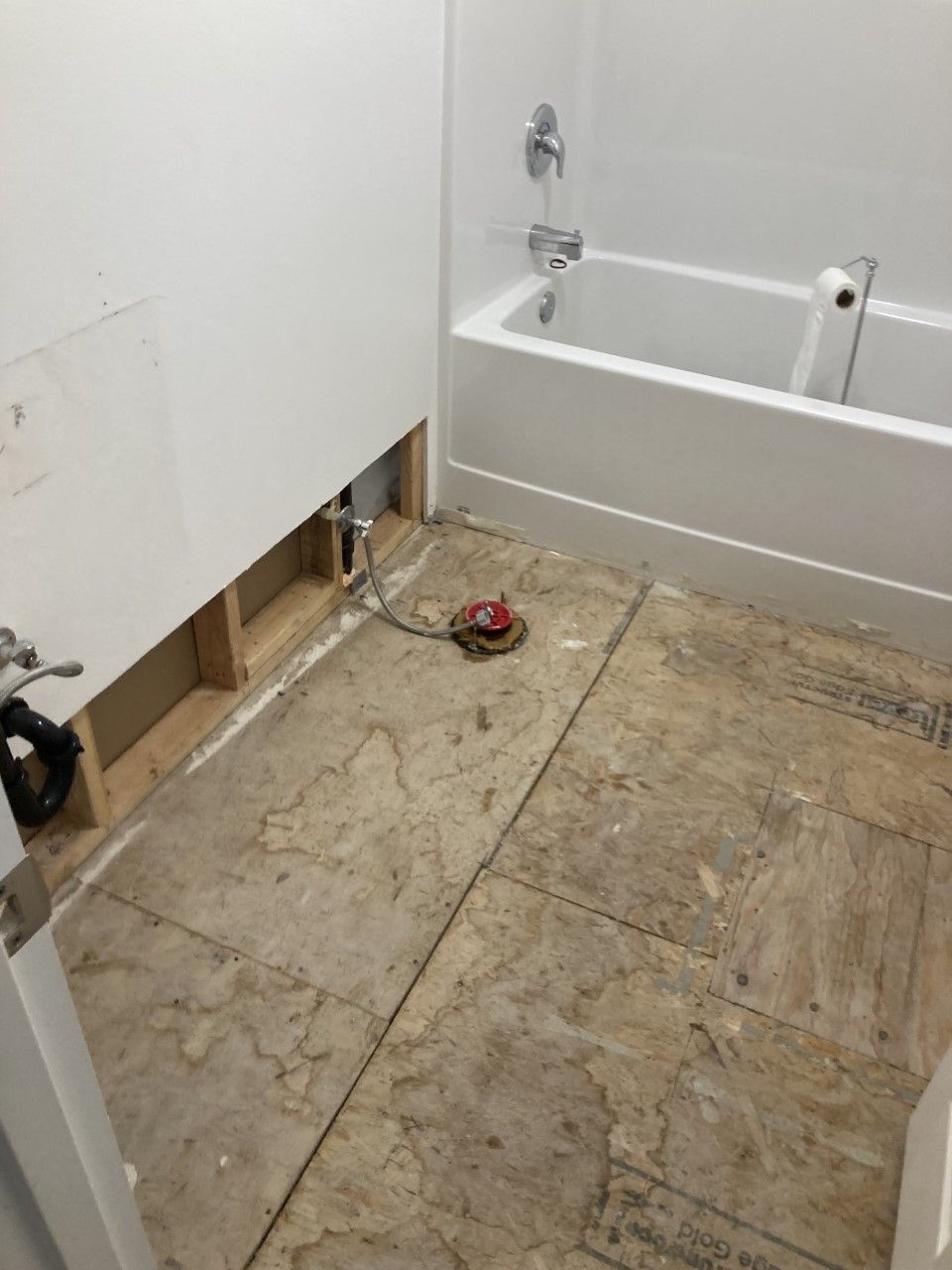 A bathroom with a bathtub and a hole in the wall