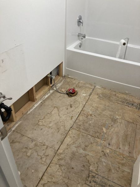 A bathroom with a bathtub and a hole in the wall