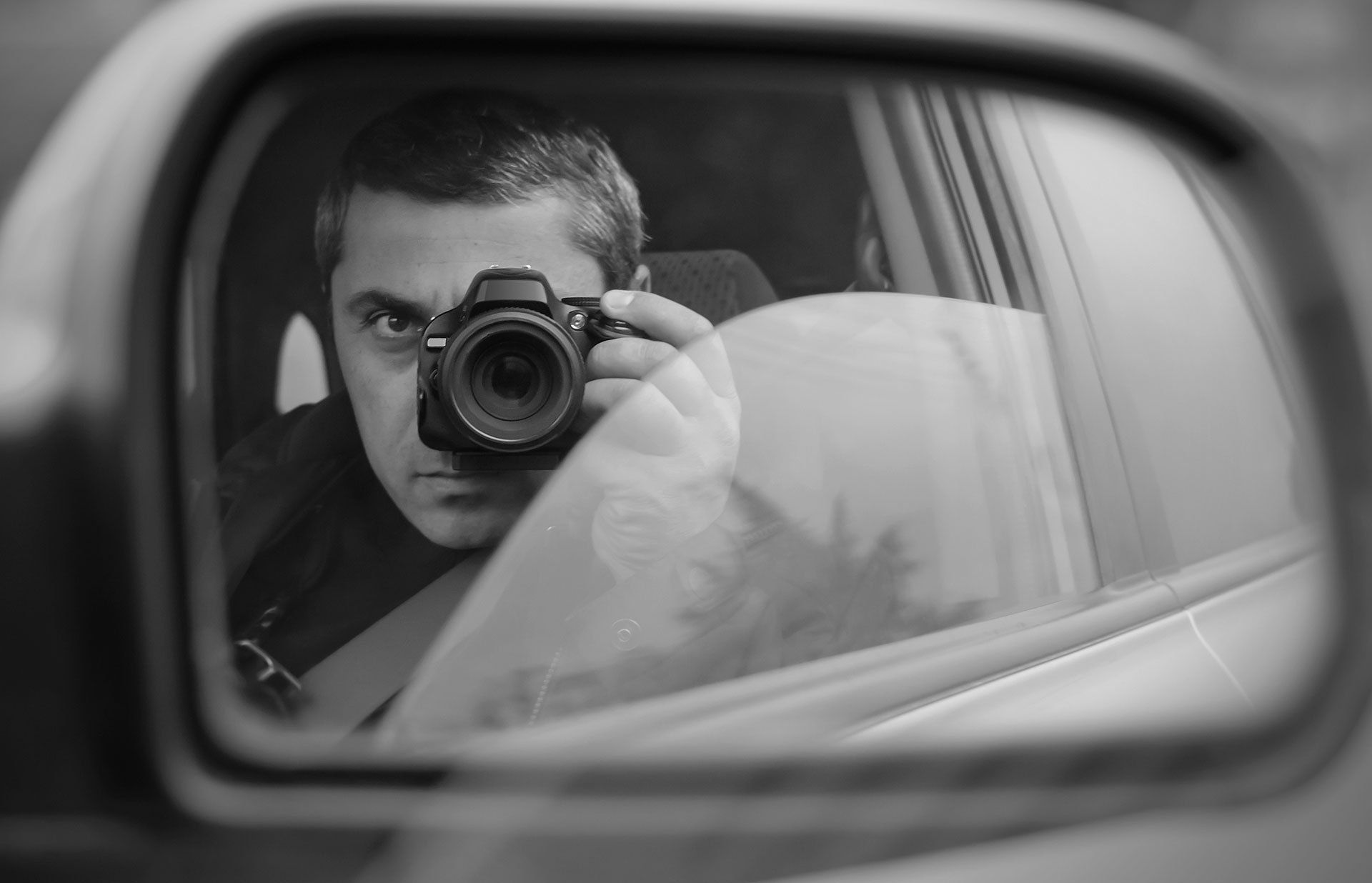 private investigator taking photographs from a car