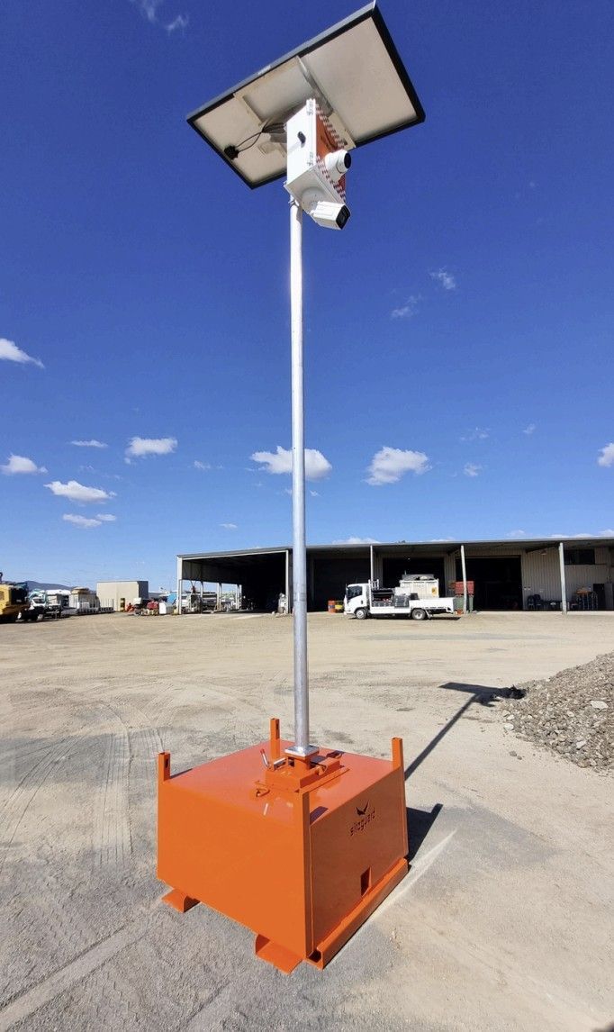 Orange solar-powered security camera system with a view of a construction site, including a bulldozer.