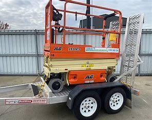 Orange Kubota mini excavator on a trailer, ready for transport. Outdoors, daytime.