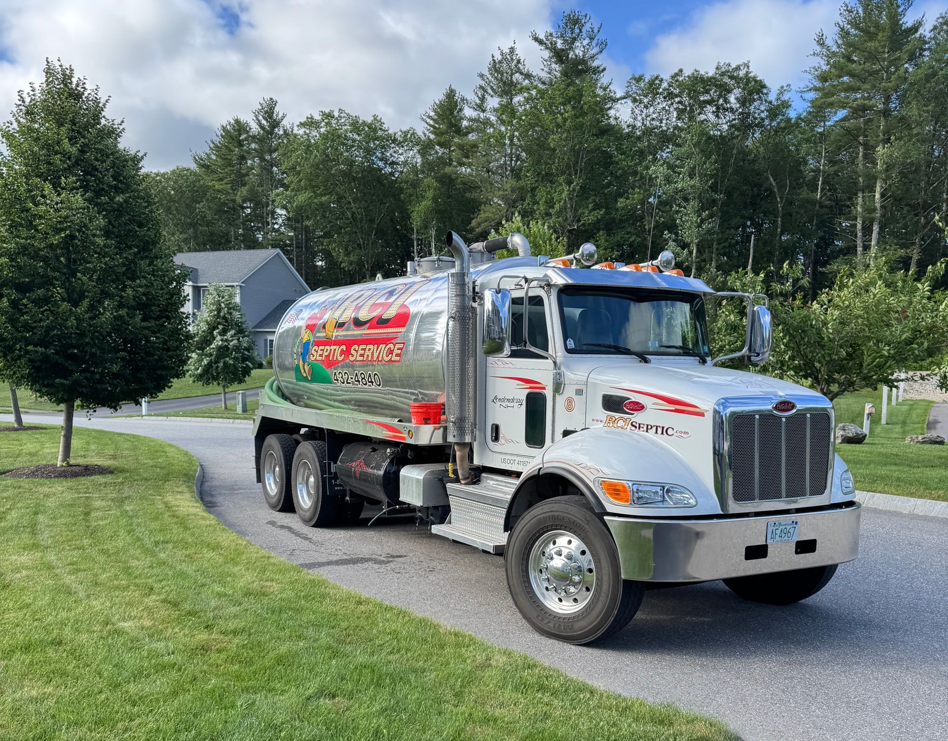 A large white septic truck is parked on the side of the road.