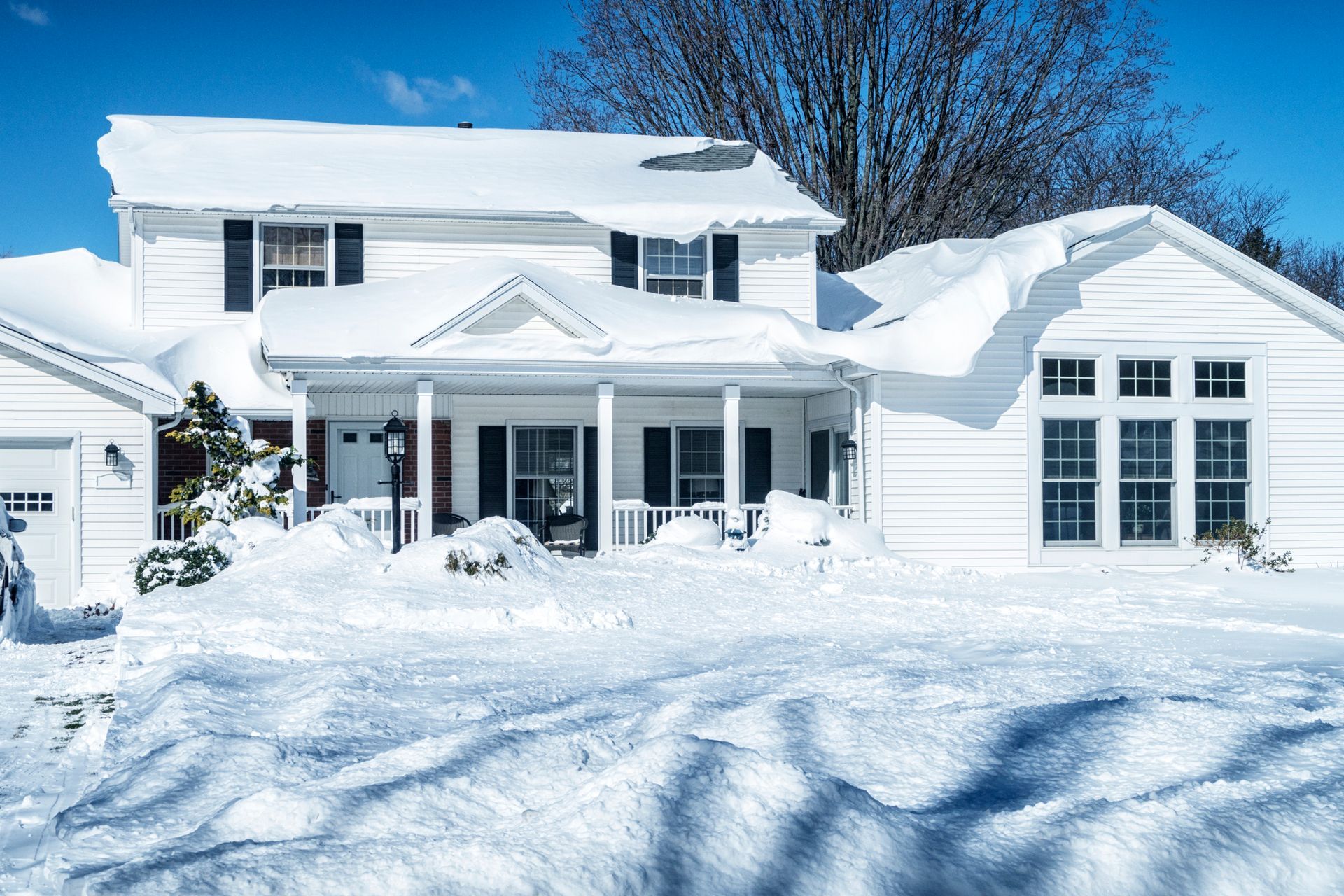 A large white house covered in snow on a sunny day.