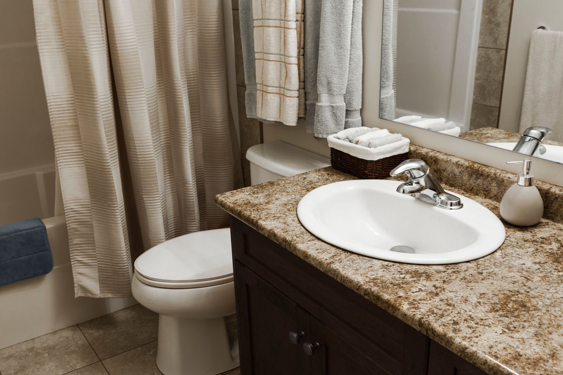 Bathroom with a sink, toilet, shower curtain, and towels in neutral tones.