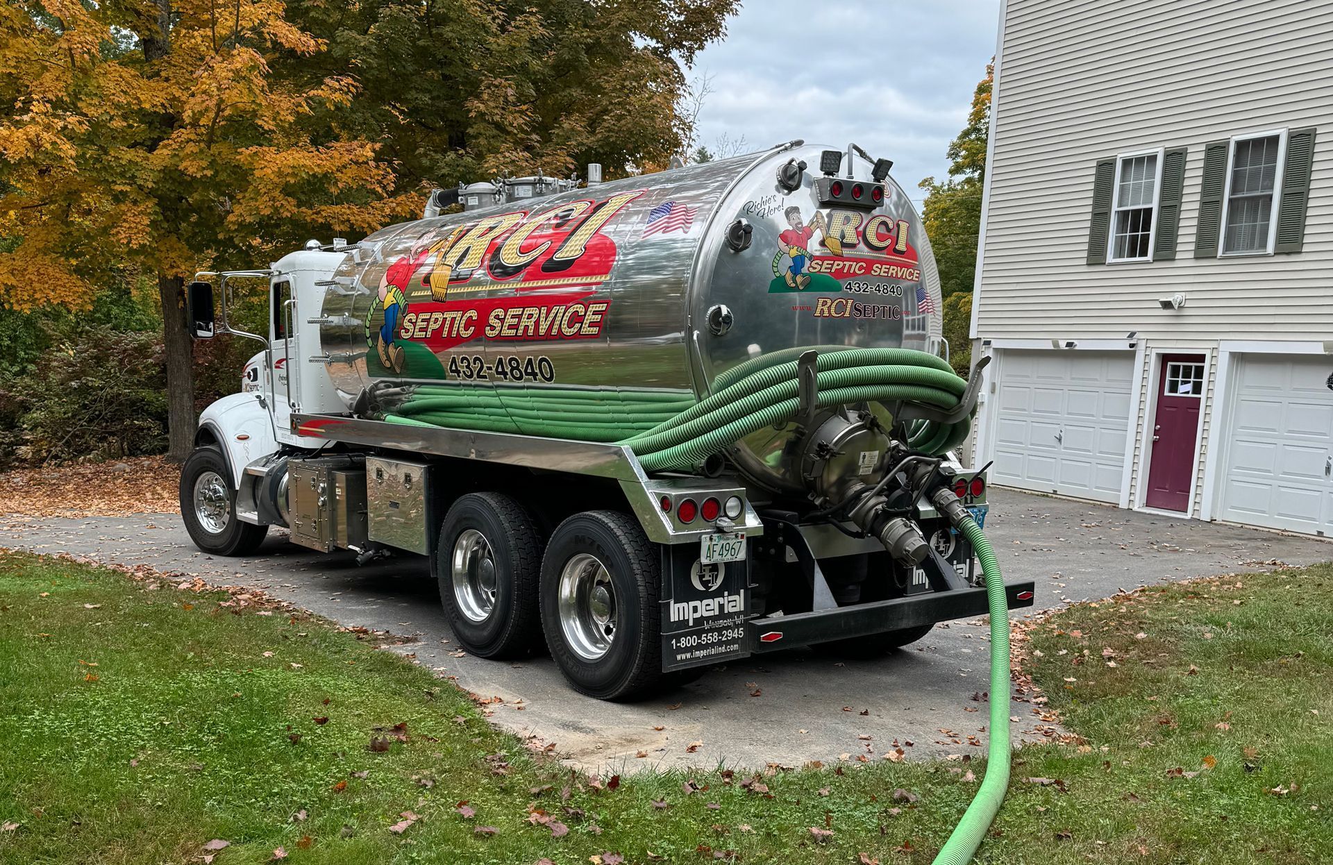 A septic tank truck is parked in front of a house.