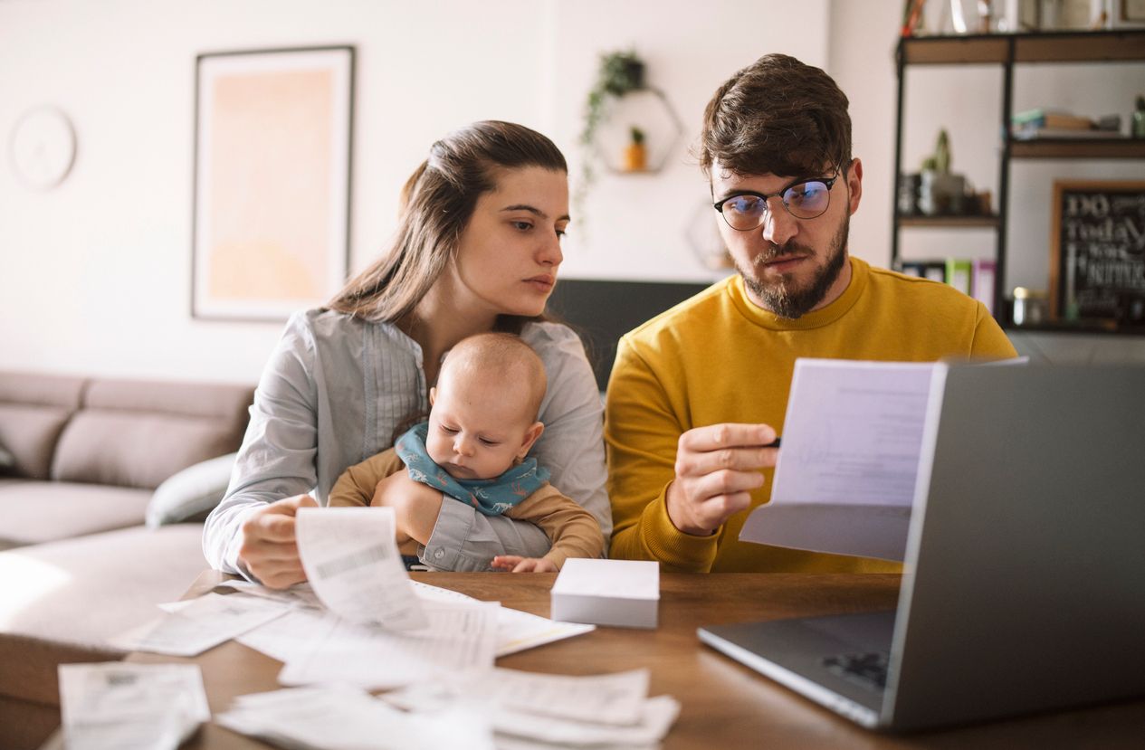 A family is sitting at a table with a baby and a laptop.