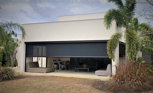 A large white house with a patio and a palm tree in front of it.