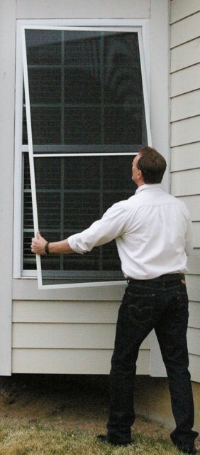 A man is standing in front of a window with a screen on it