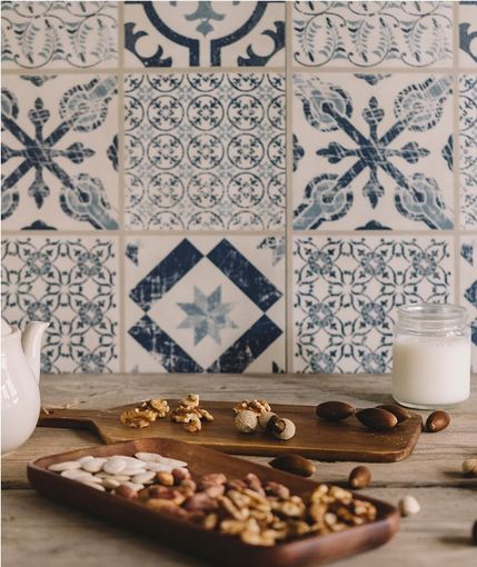 Nuts on wooden boards, jar of milk, and blue tile backsplash.