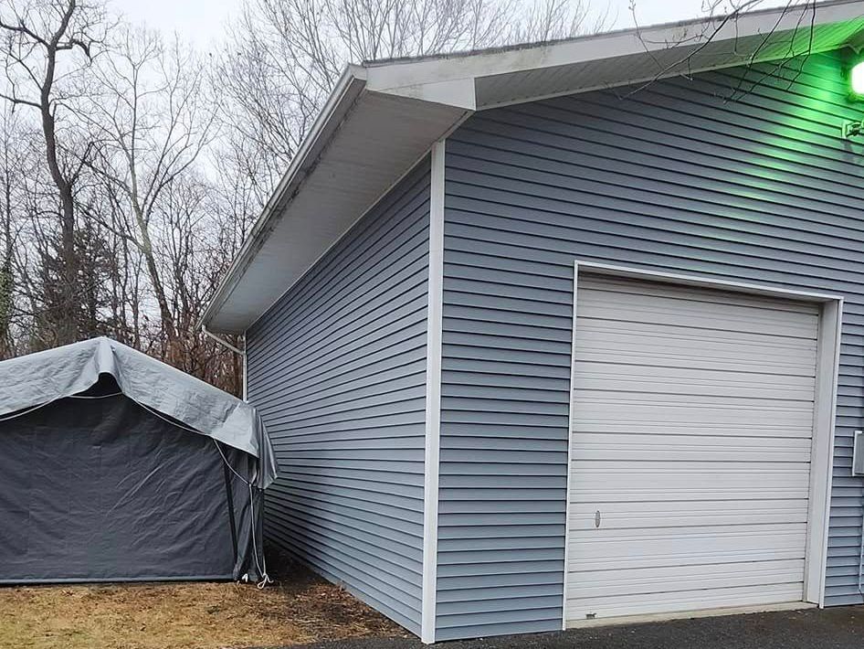 A garage with a white garage door and a tent in front of it.