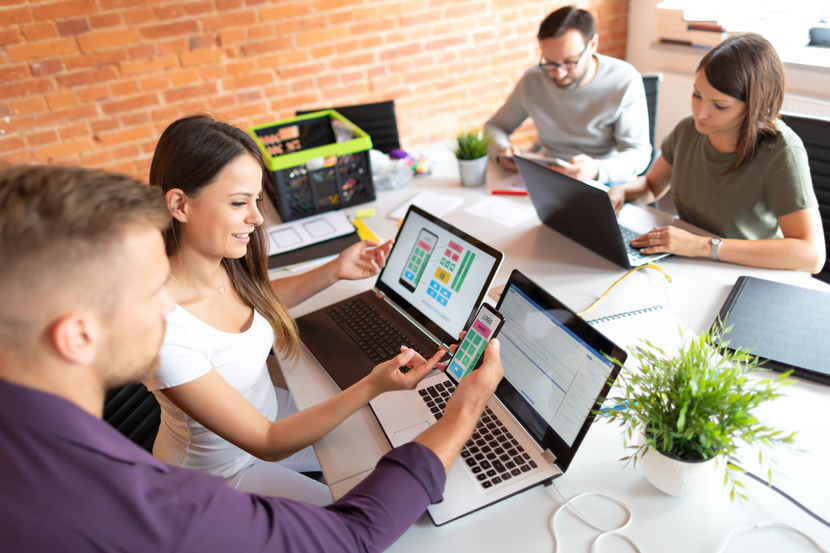 A group of people are sitting at a table with laptops.