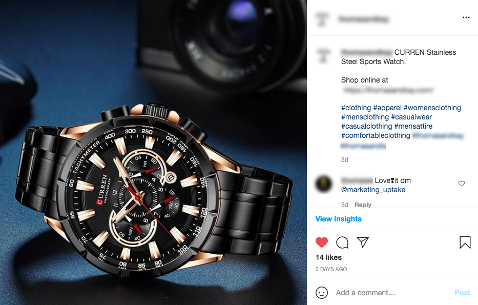 A black and gold watch is sitting on a blue table next to a camera.