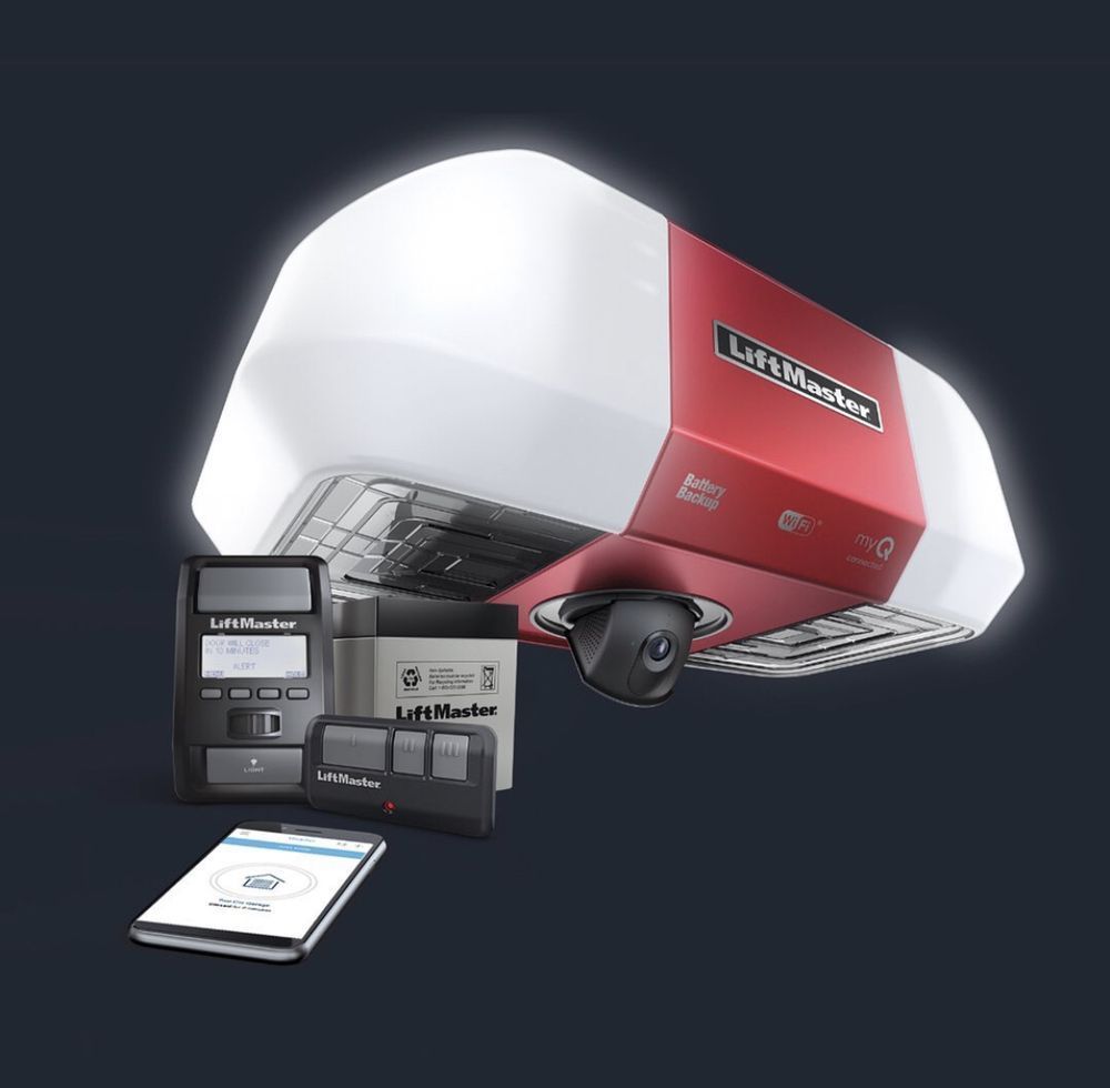 A red garage door opener is sitting next to a cell phone.