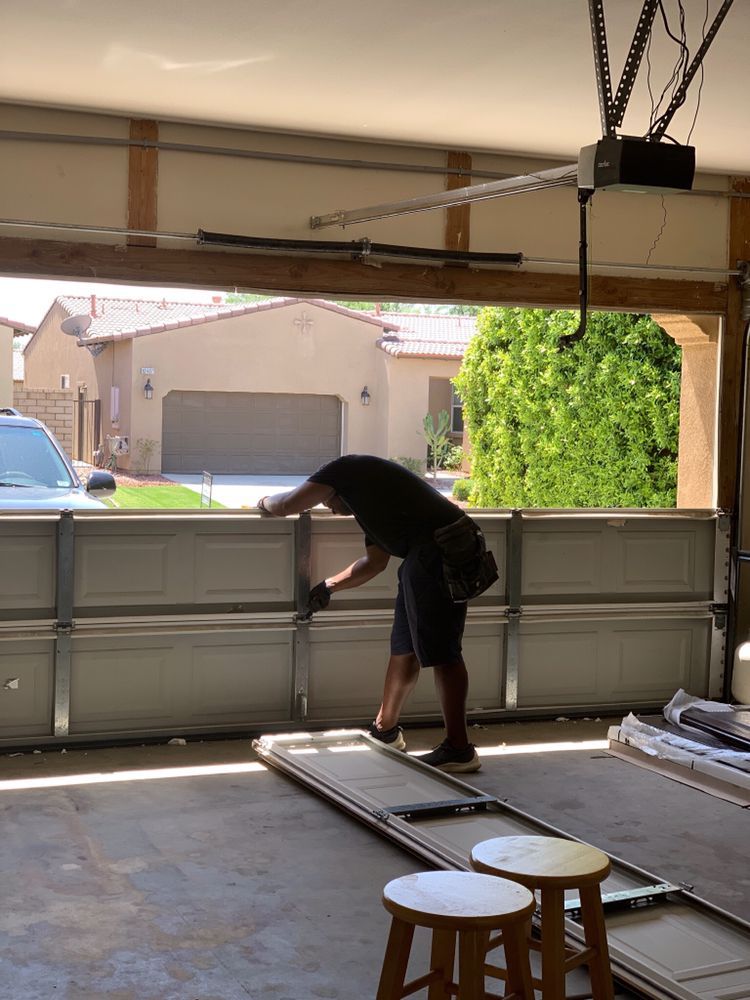 A man in a black shirt is working on a garage door