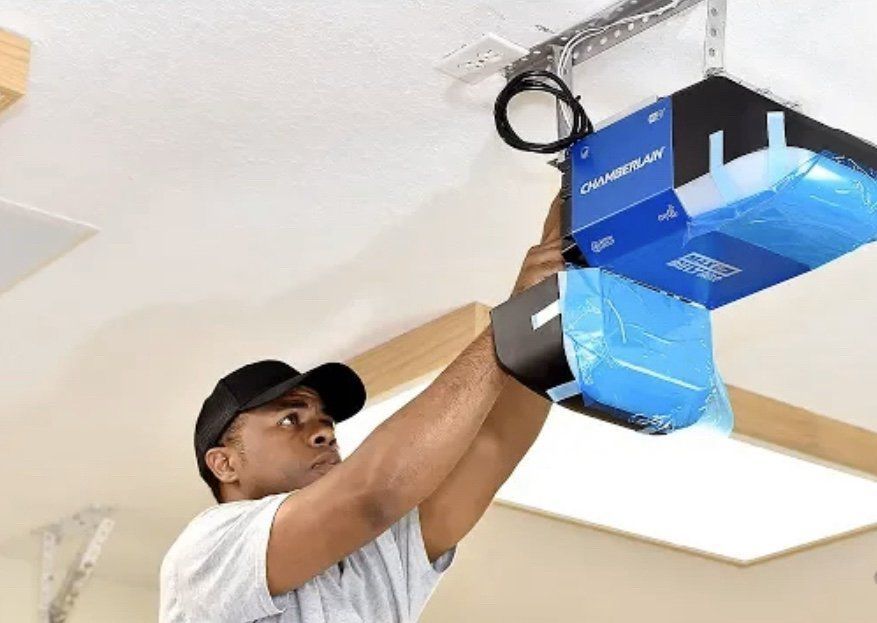 A man is installing a garage door opener on the ceiling.