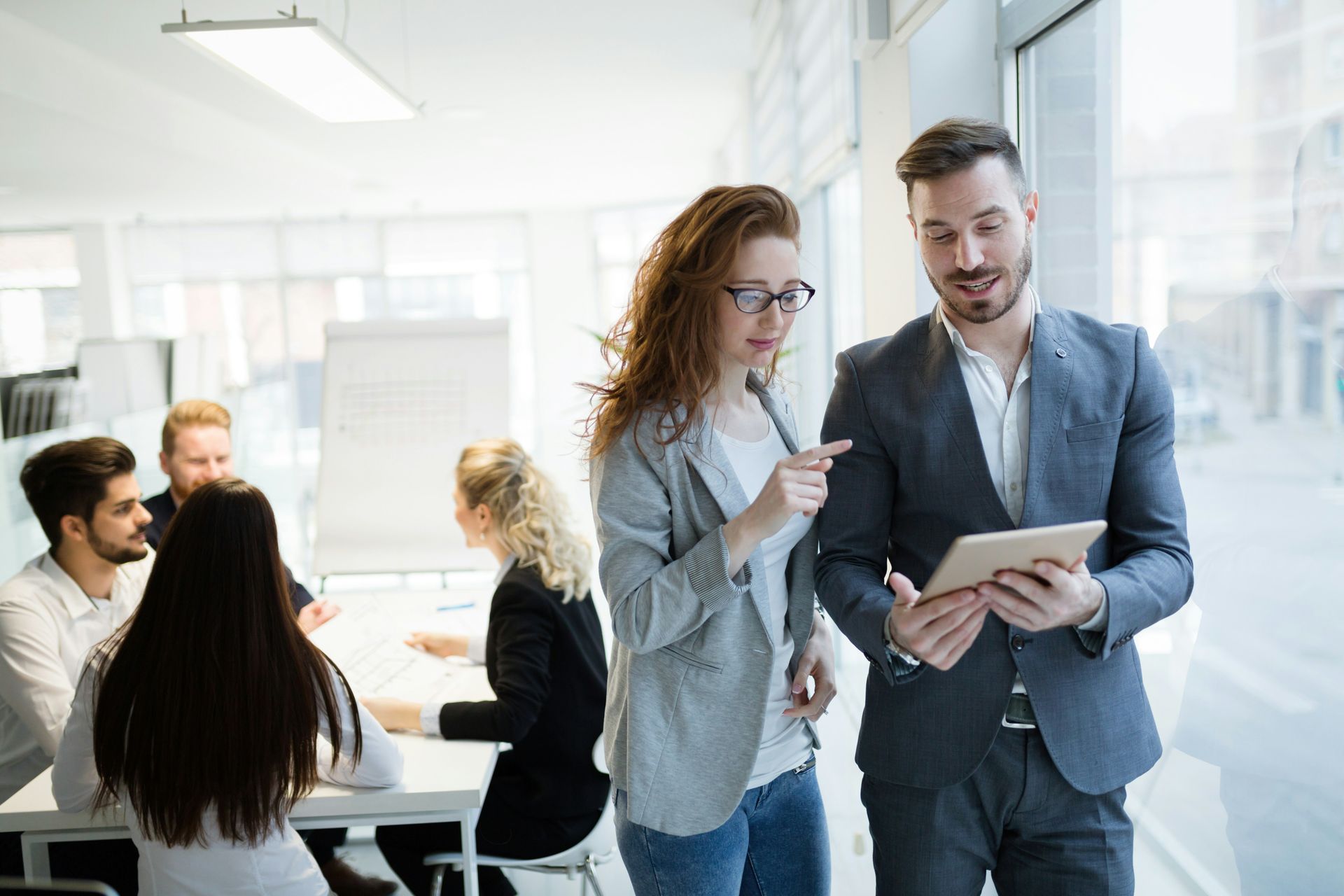 High-rise building under construction with two cranes against a clear blue sky.