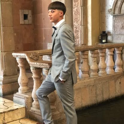 A man in a suit and tie is standing next to a railing.