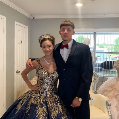 A man in a suit and bow tie is standing next to a woman in a ball gown.