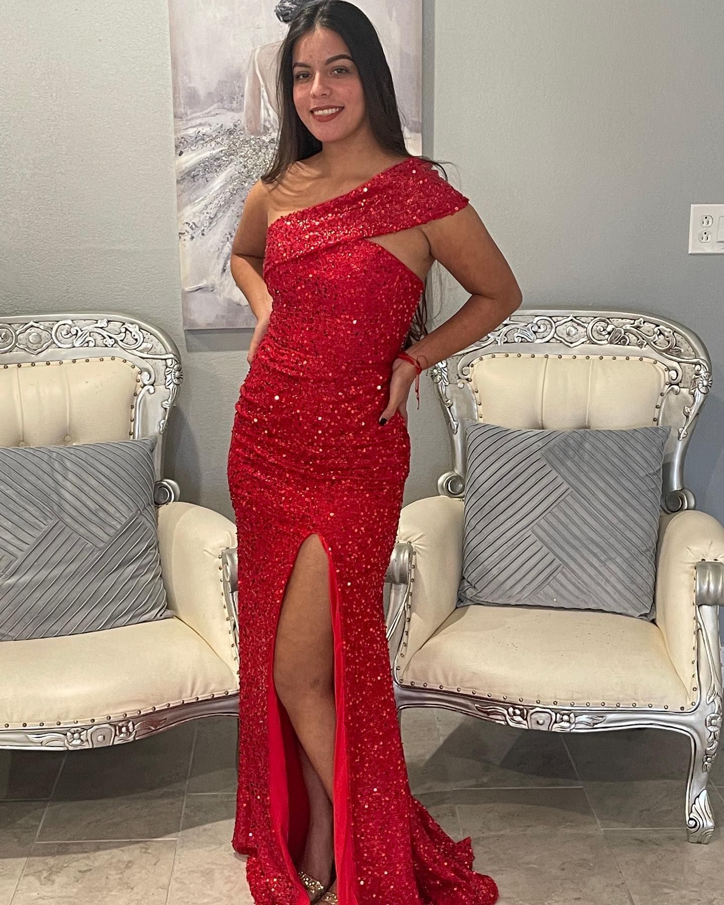 A woman in a red dress is standing in front of two chairs.