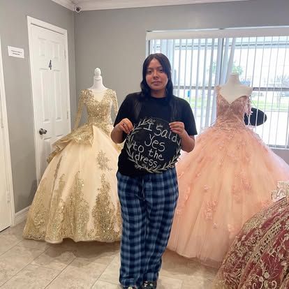 A woman is standing in a room with dresses and holding a sign that says `` i said yes to the dress ''.